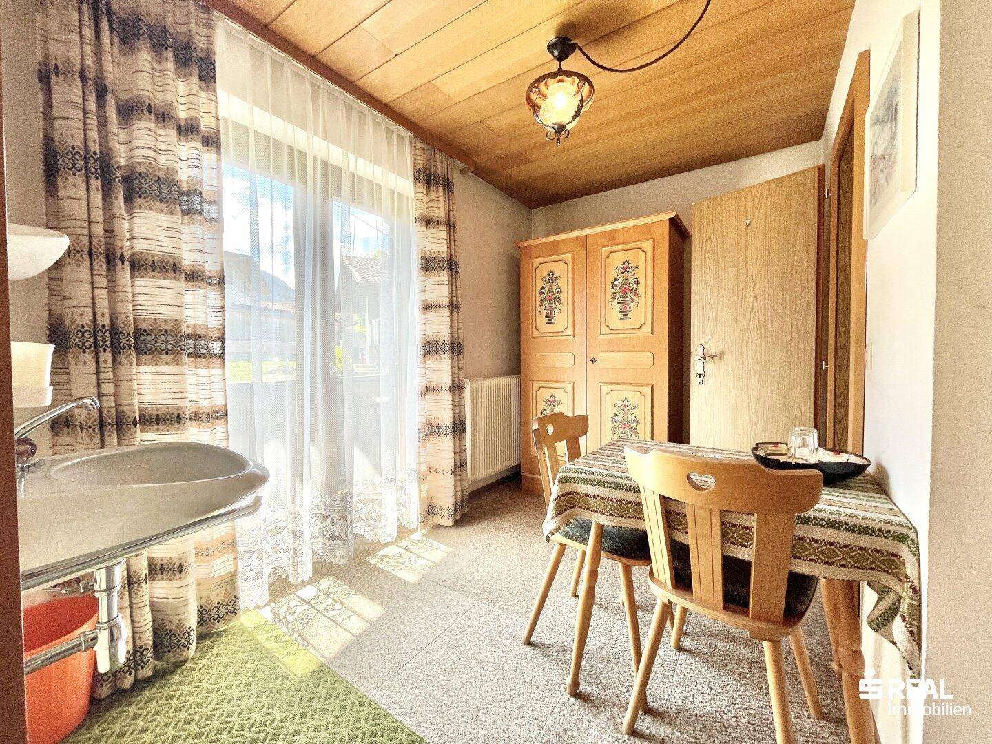 Heller Raum mit kleinem Essbereich, Waschbecken und traditionellem Holzschrank.