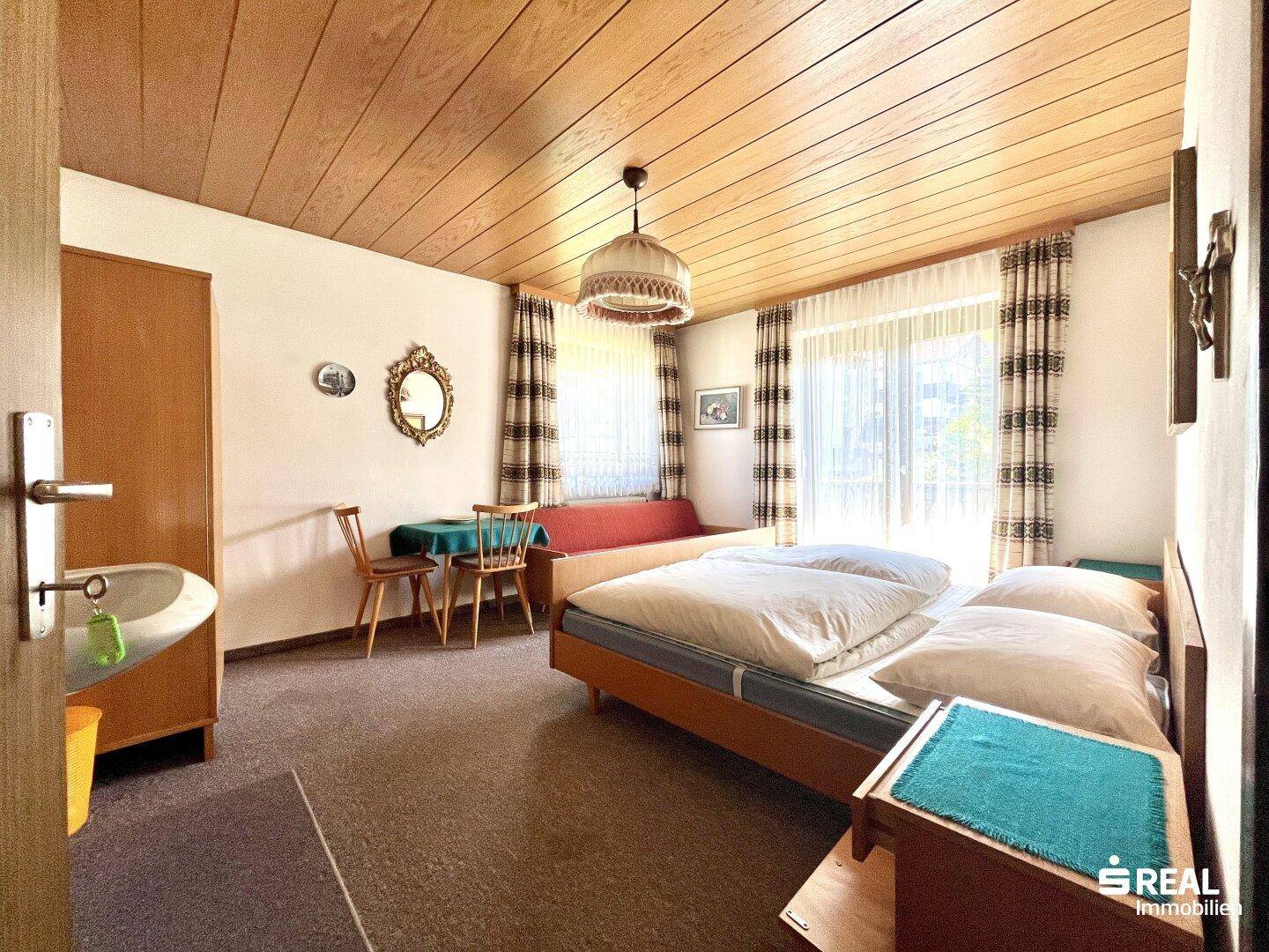 Schlafzimmer mit Doppelbett, kleinem Essbereich und integriertem Waschbecken.