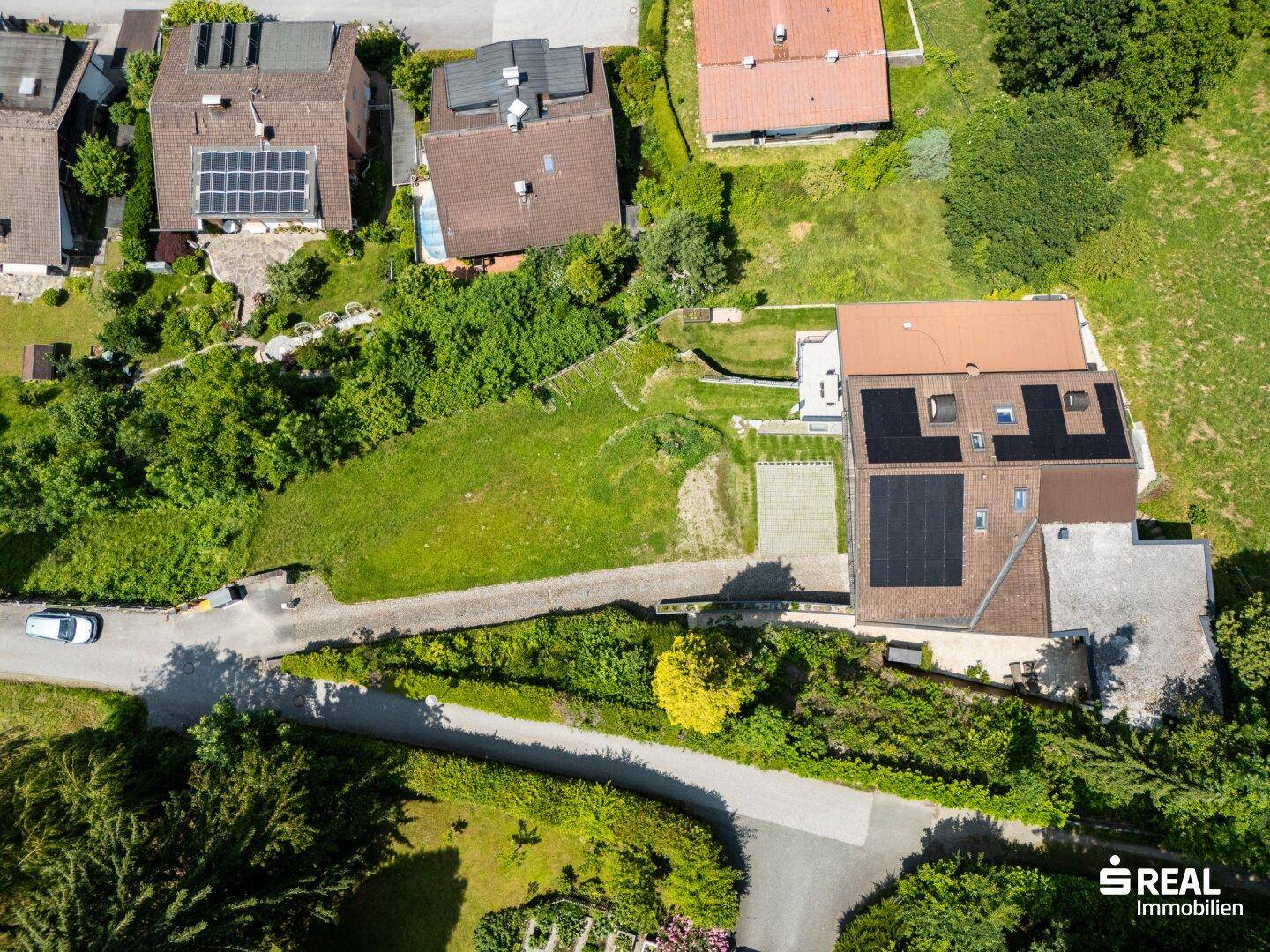 Luftaufnahme eines Wohnhauses mit Solaranlagen auf dem Dach, umgeben von Gärten und Nachbarhäusern.