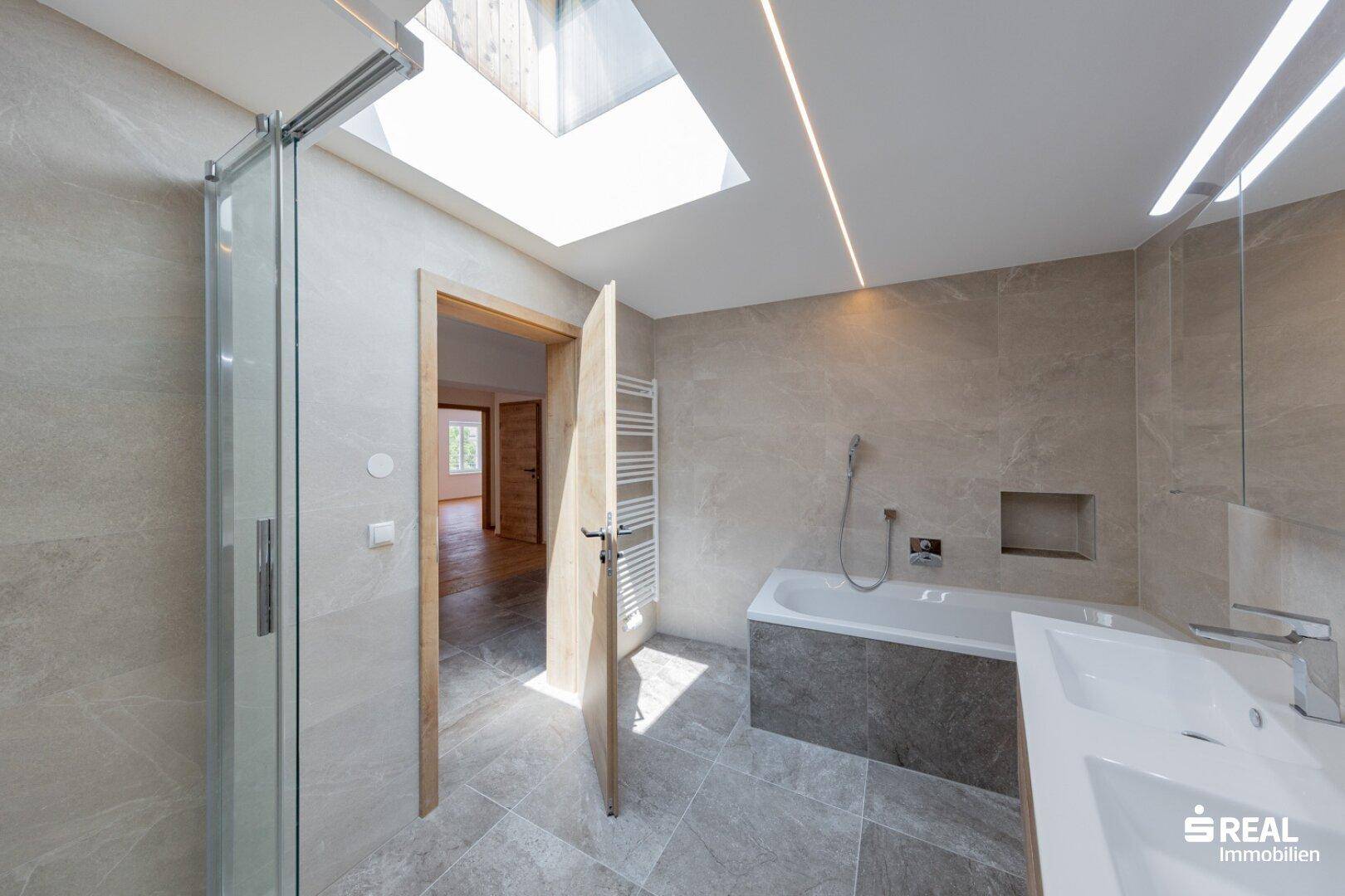 Helles Badezimmer mit Dusche, Badewanne und Oberlicht, das viel natürliches Licht hereinlässt.