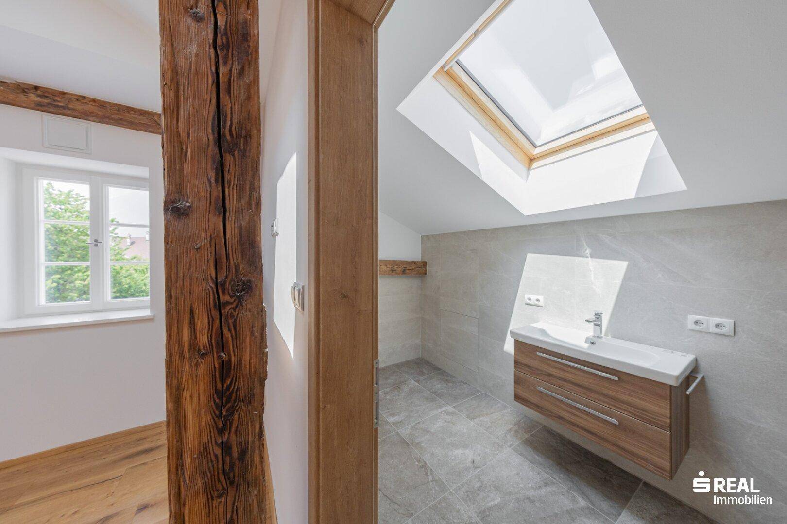 Modernes Badezimmer im Dachgeschoss mit Waschtisch, Fliesenboden und Oberlicht.