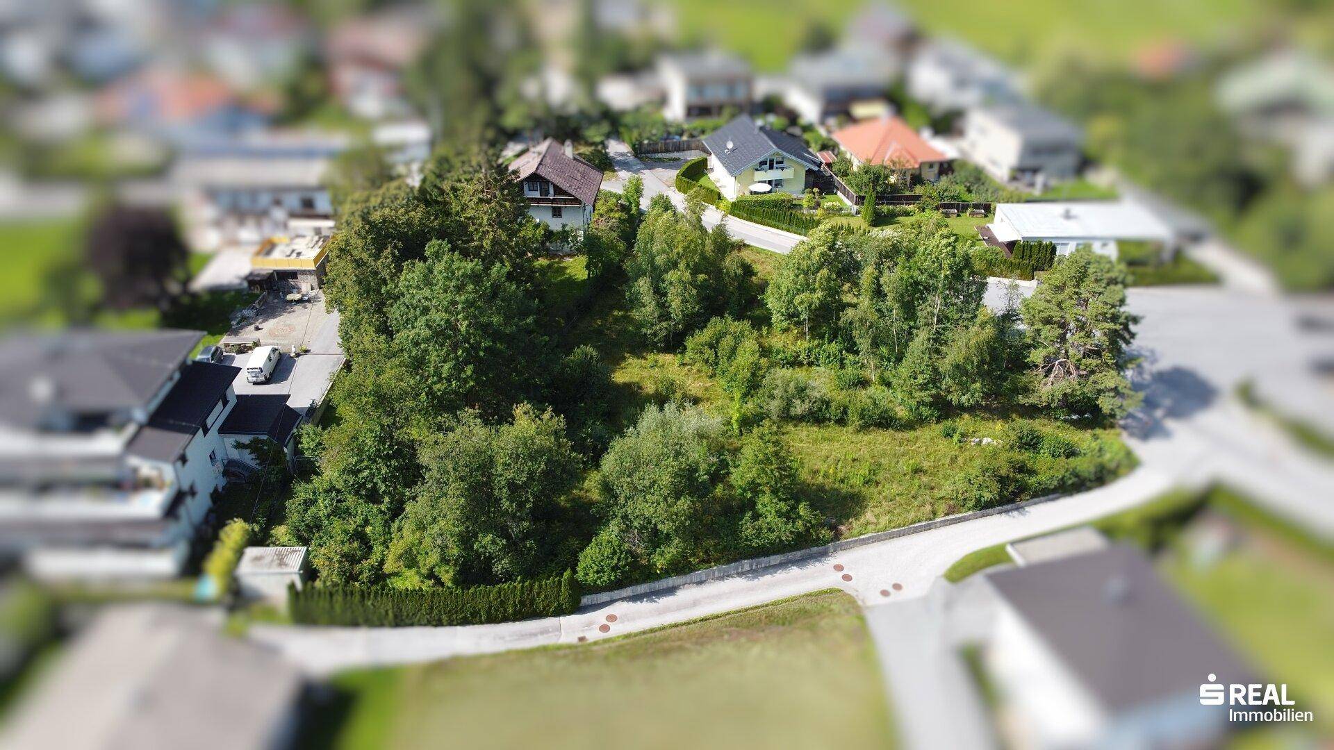 Übersicht aus der Vogelperspektive eines Wohngebiets mit unbebautem Grundstück, umgeben von Häusern und Straßen.