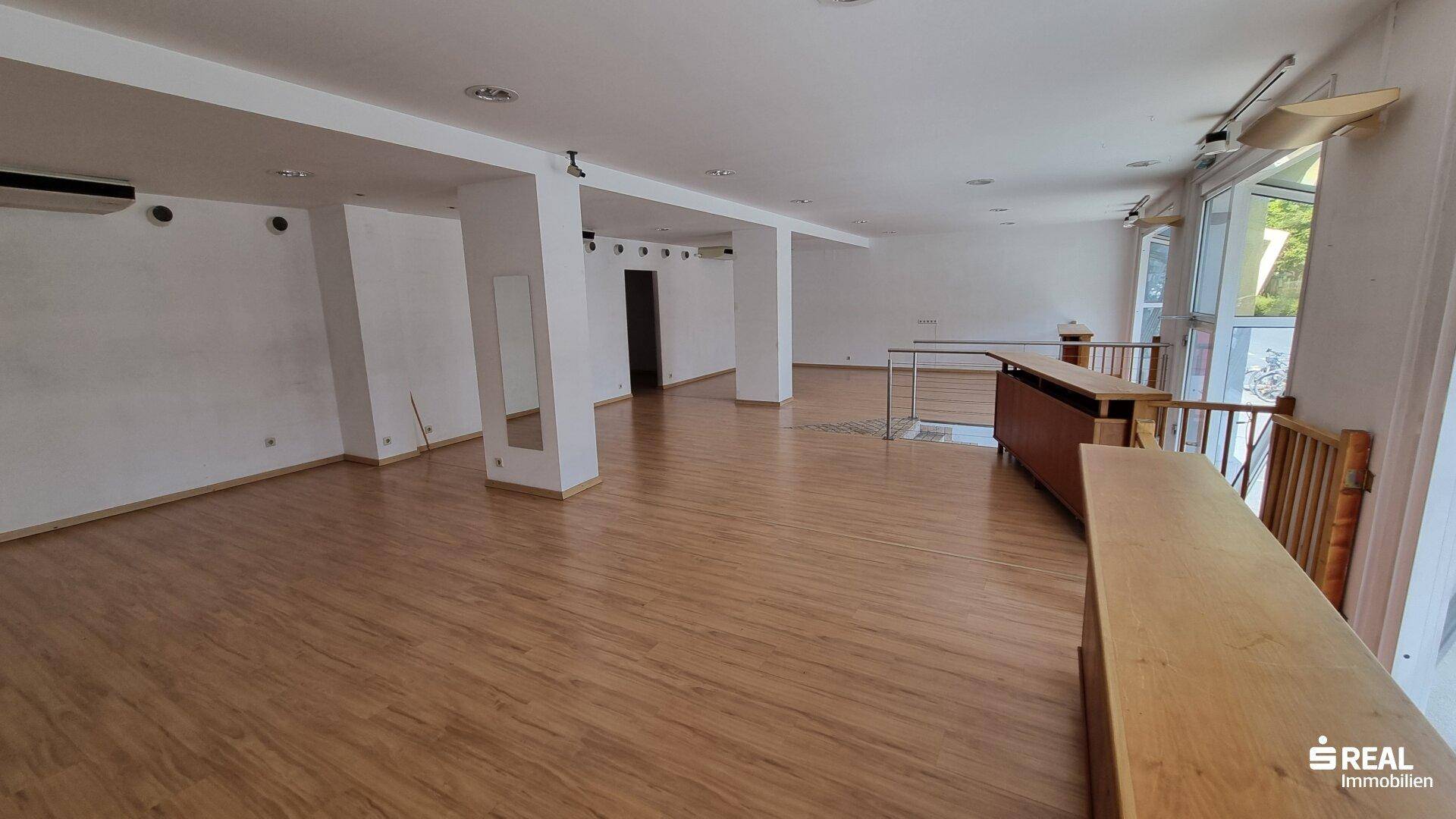 Geräumiger, heller Innenraum mit Säulen, Laminatboden und Klimaanlage an der Wand.