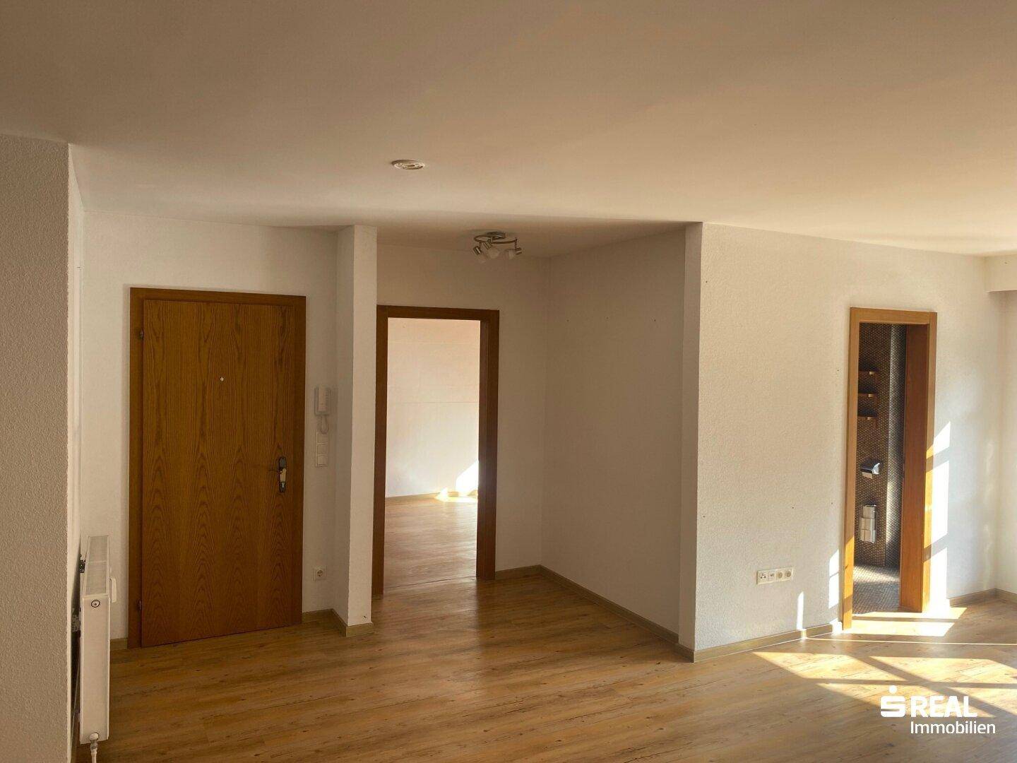 Heller Flurbereich mit Holztüren und Parkettboden, der zu den angrenzenden Räumen führt.