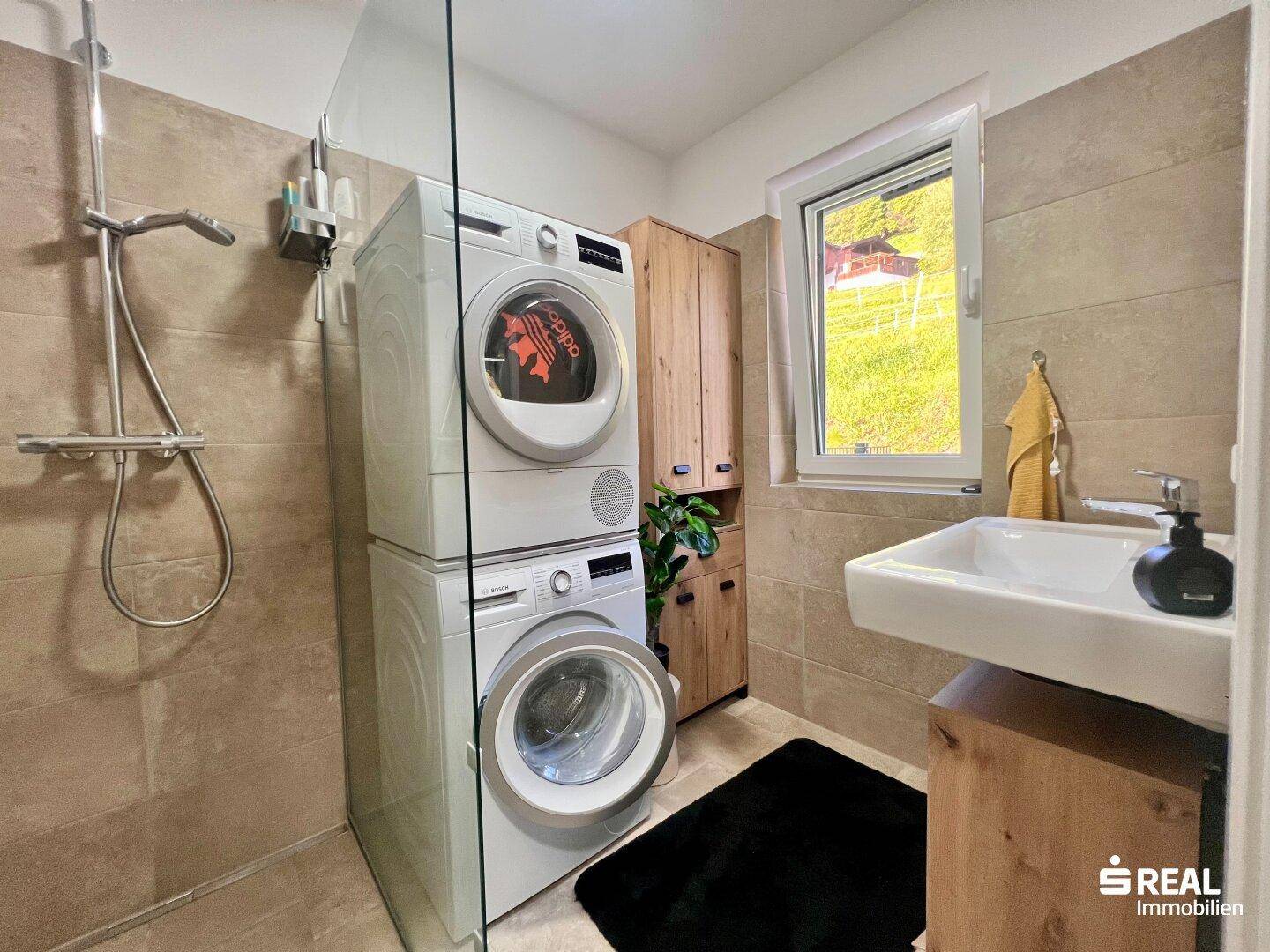 Modernes Badezimmer mit Dusche, Waschmaschine, Trockner und Fenster.