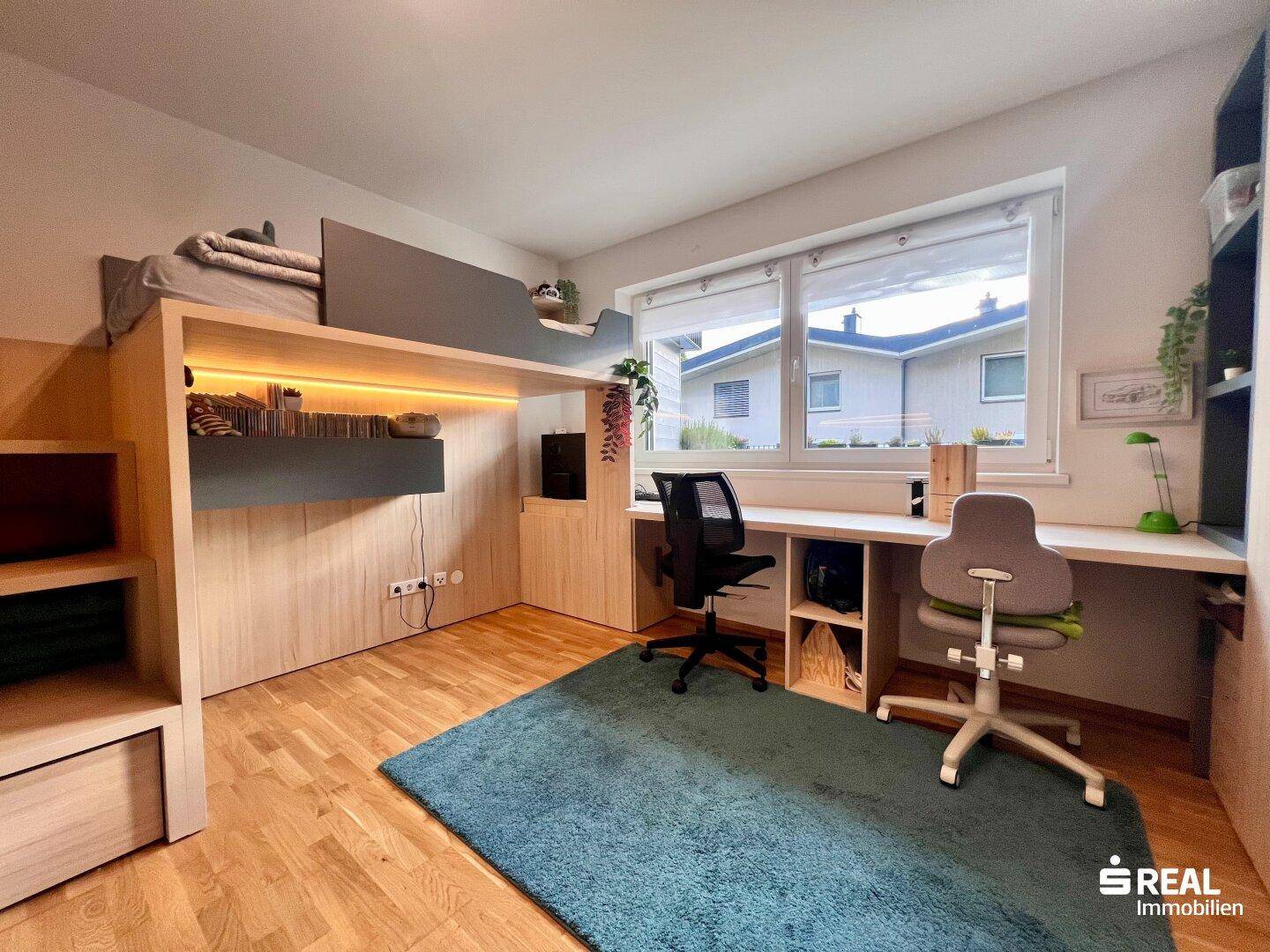 Jugendzimmer mit Hochbett, zwei Schreibtischen und Holzboden.