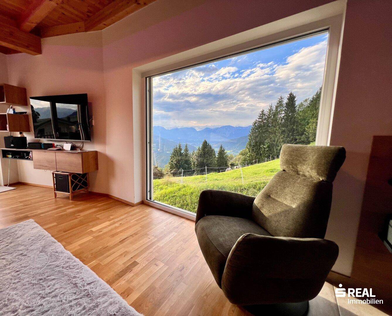 Gemütlicher Wohnbereich mit großem Panoramafenster und atemberaubendem Blick auf die Berglandschaft.