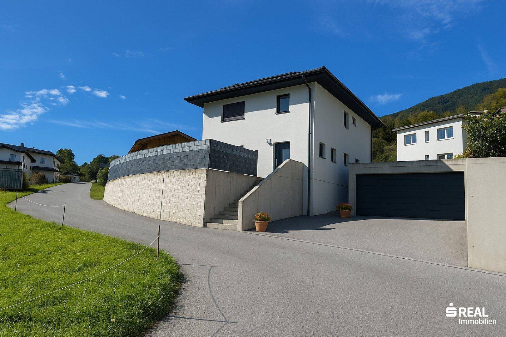 Ansicht des modernen Hauses mit Garage, Zufahrt und Treppenaufgang in sonniger Lage.