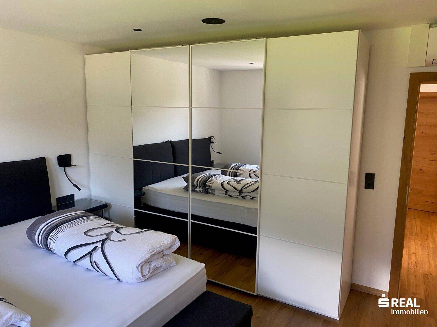 Schlafzimmer mit großem Bett und Spiegelschränken, die den Raum optisch vergrößern.