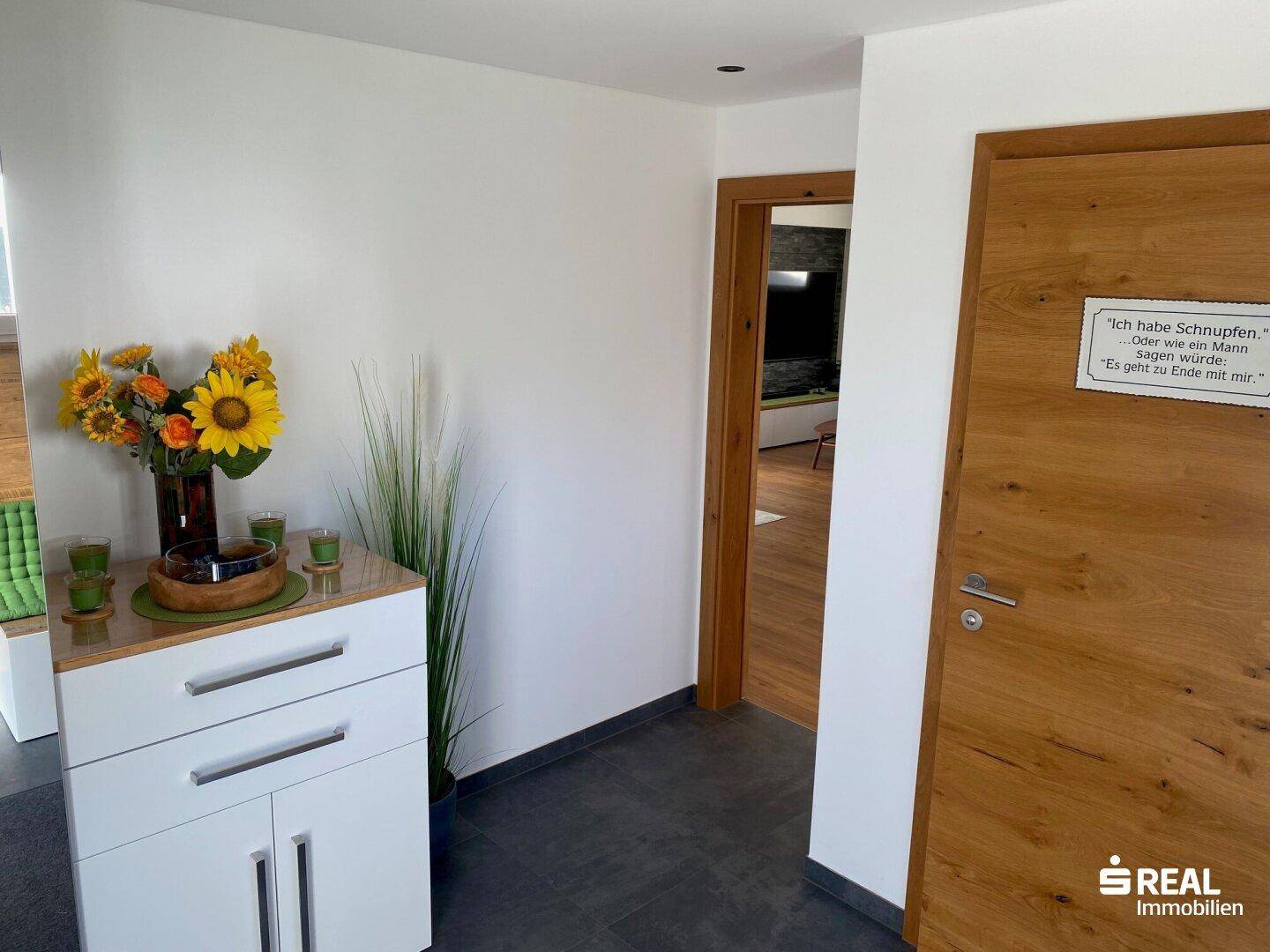 Heller Flur mit Holztüren und dunklem Fliesenboden, einladend und funktional gestaltet.