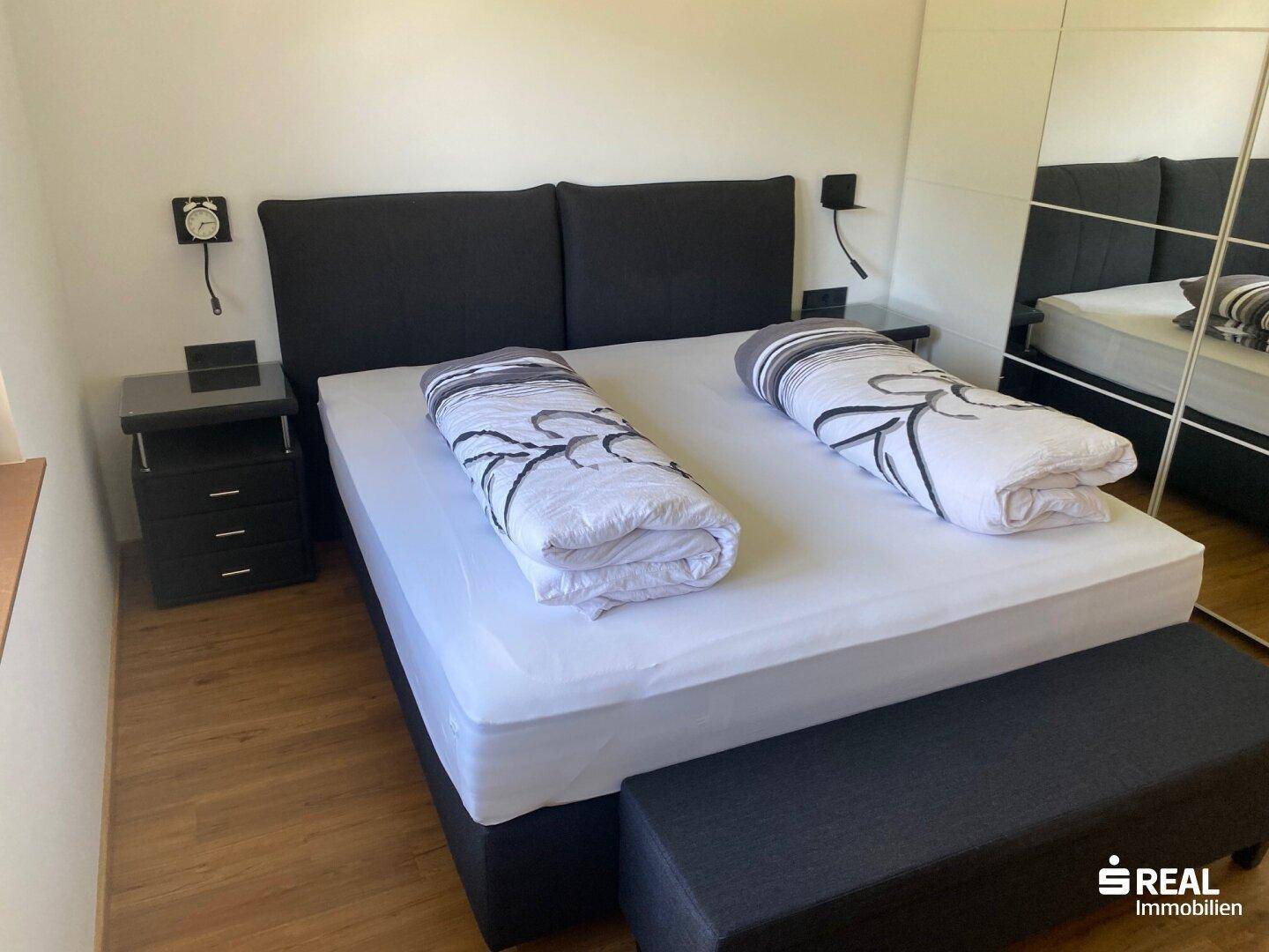 Schlafzimmer mit Doppelbett, Nachttischen und Spiegelschränken, gemütlich und funktional.