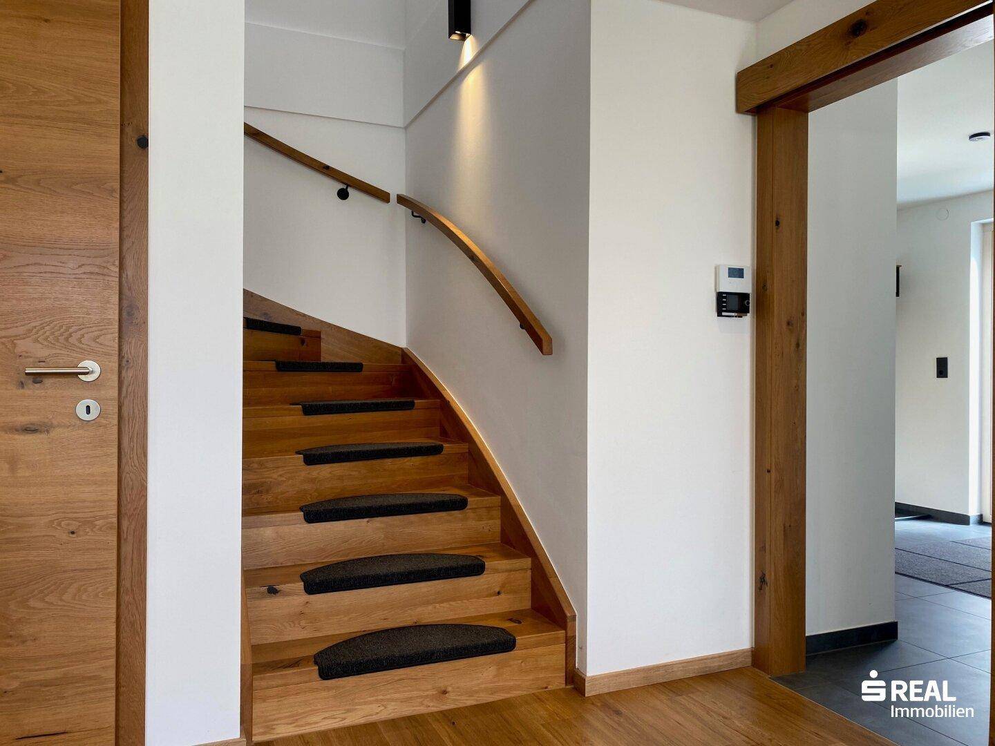 Heller Eingangsbereich mit Holztreppe und Holztüren, einladend und modern gestaltet.