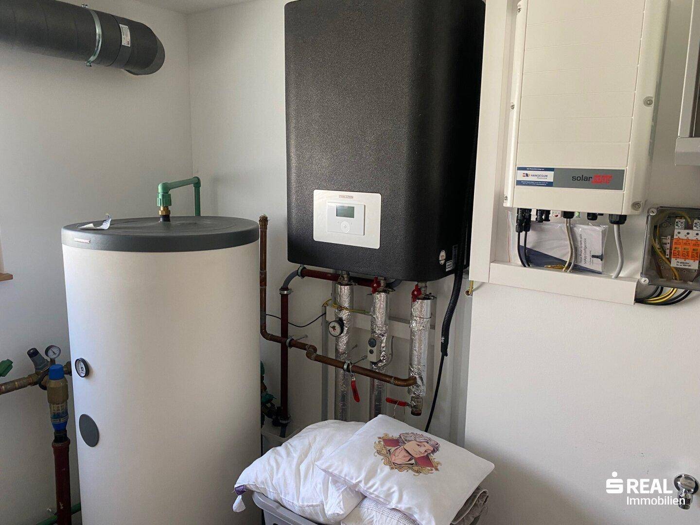 Technikraum mit Warmwasserspeicher, Wärmepumpe und Photovoltaik-Steuerung.