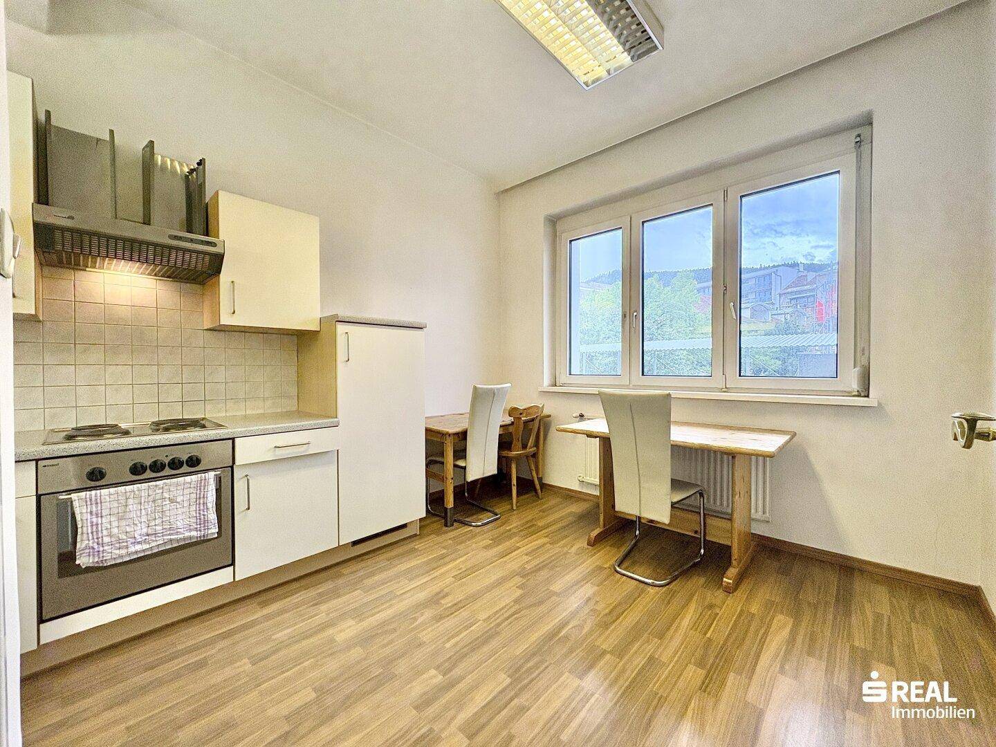 Helle Küche mit Essbereich, Holzboden und großem Fenster für viel Tageslicht.