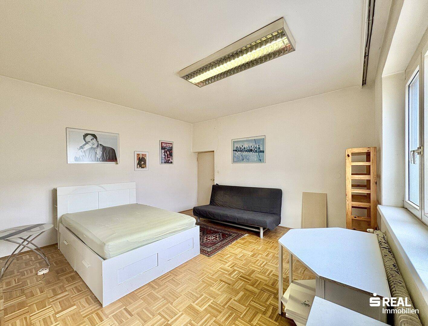 Helles Schlafzimmer mit Parkettboden, großem Bett und Sofa, bietet viel Platz.