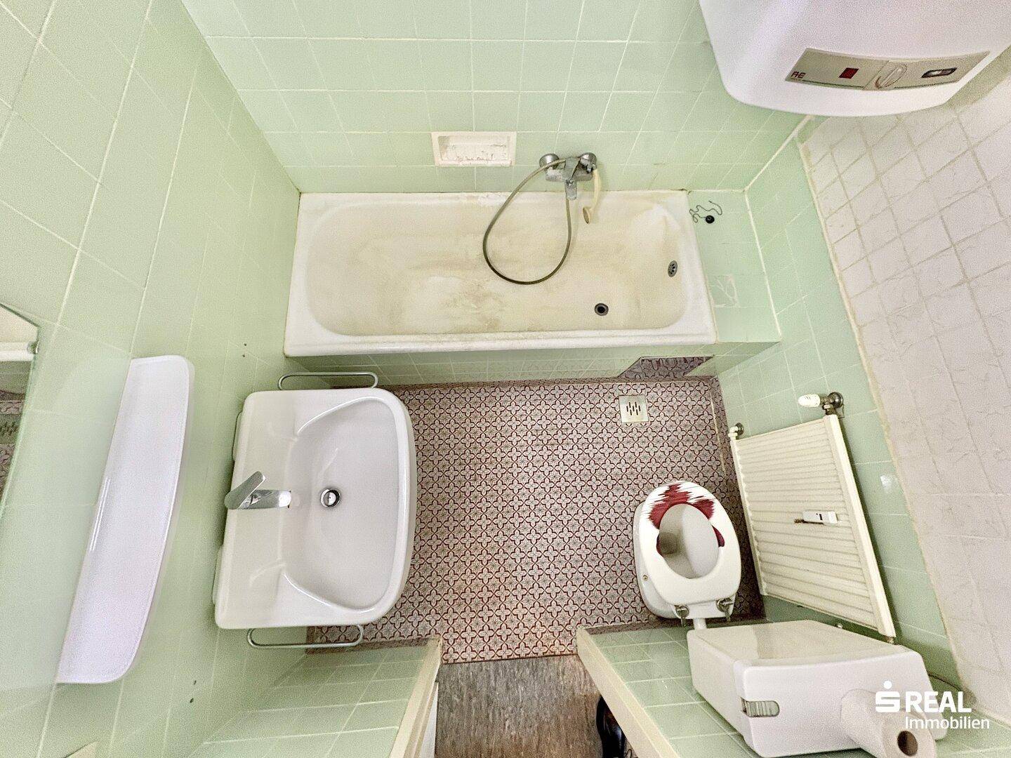 Badezimmer von oben gesehen mit Badewanne, Waschbecken und WC, in älterem Stil.