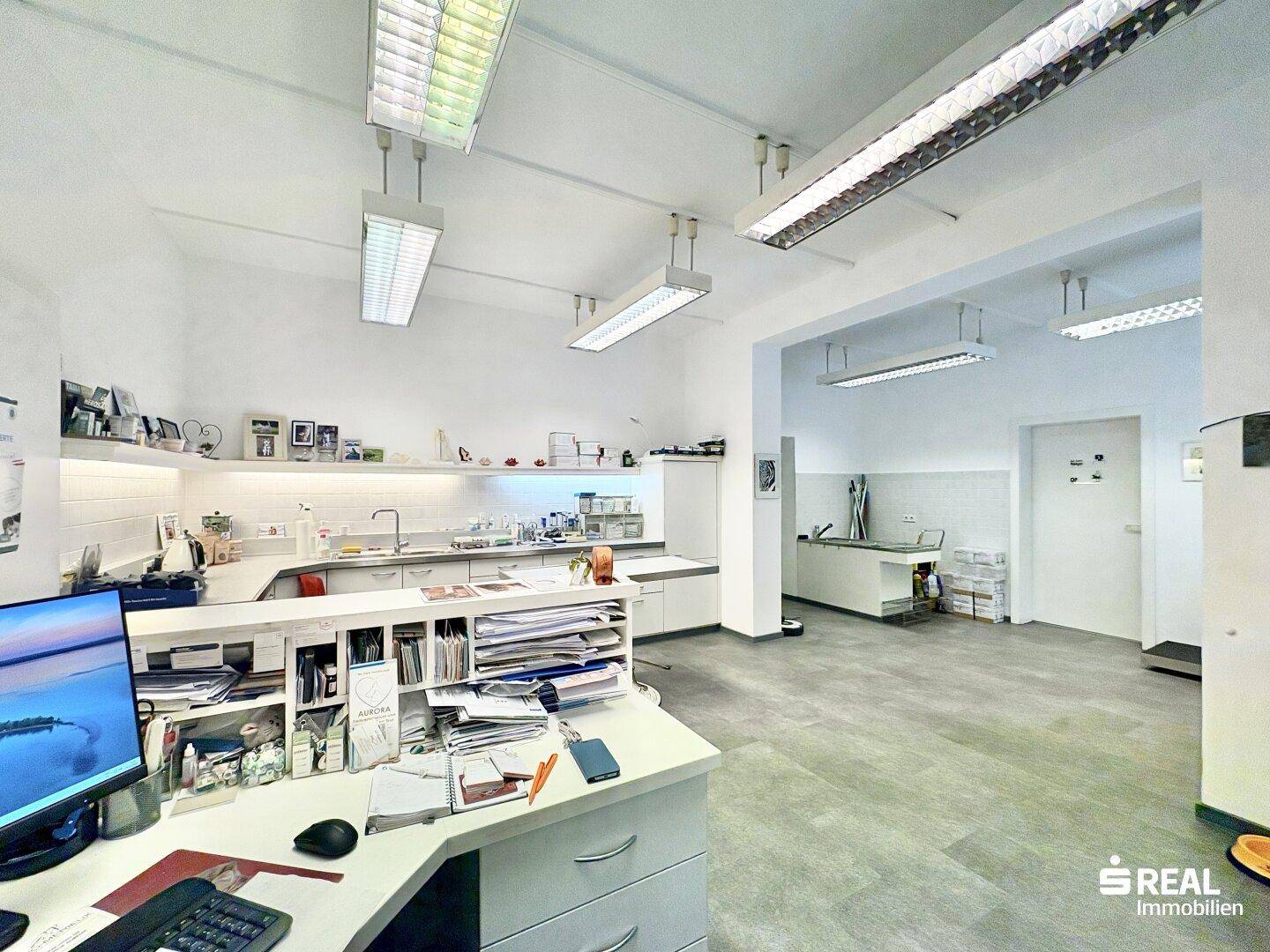 Geräumiger Arbeitsbereich mit Empfangstheke, Schränken und Blick in weitere Räume.
