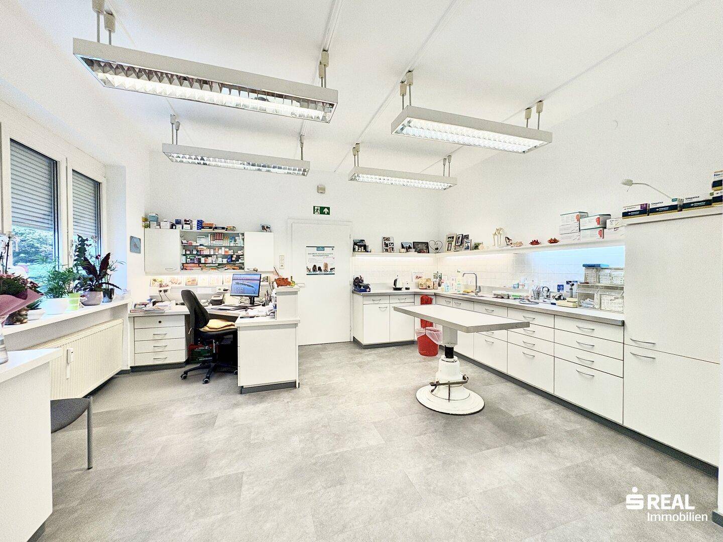 Geräumiger Arbeitsraum mit Schreibtisch, langen Arbeitsflächen und medizinischen Schränken.