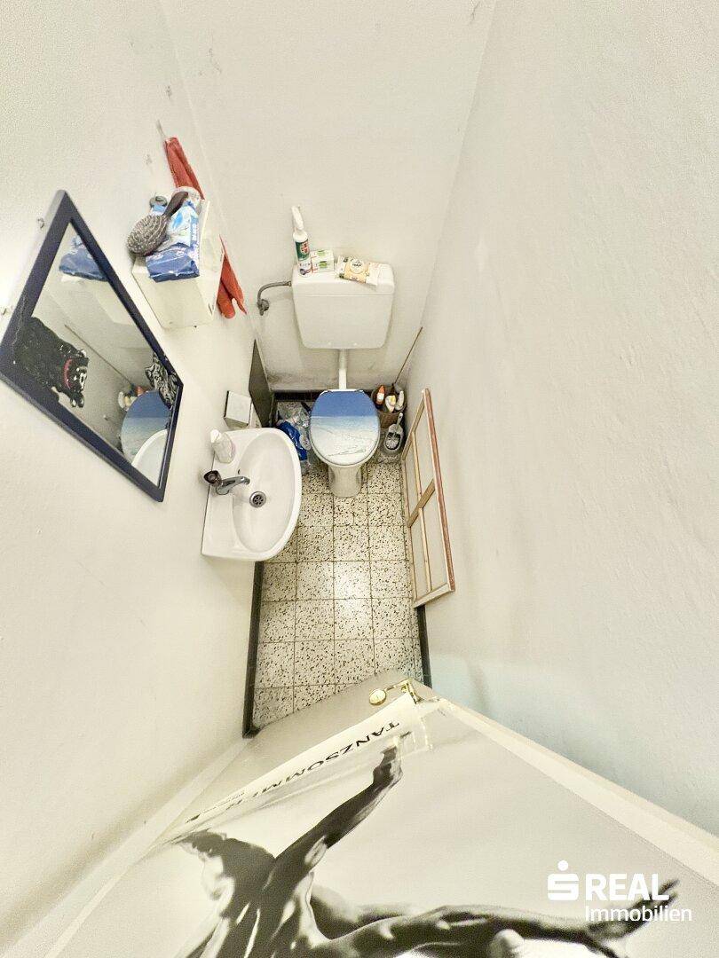 Kleines separates WC mit Waschbecken und Spiegel, funktional und platzsparend.