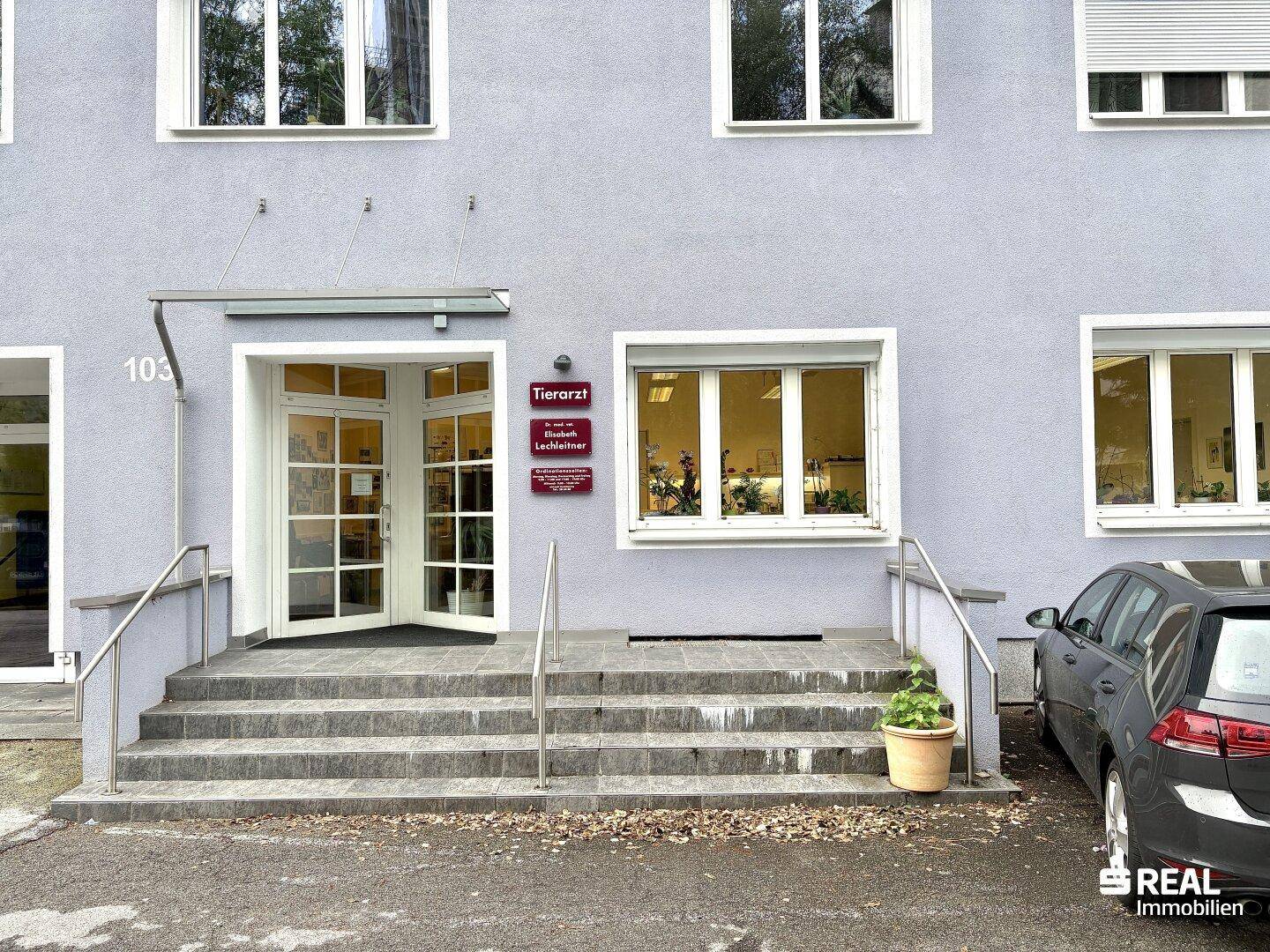 Eingangsbereich eines Gebäudes mit Treppe, Rampe und Beschilderung für eine Tierarztpraxis.