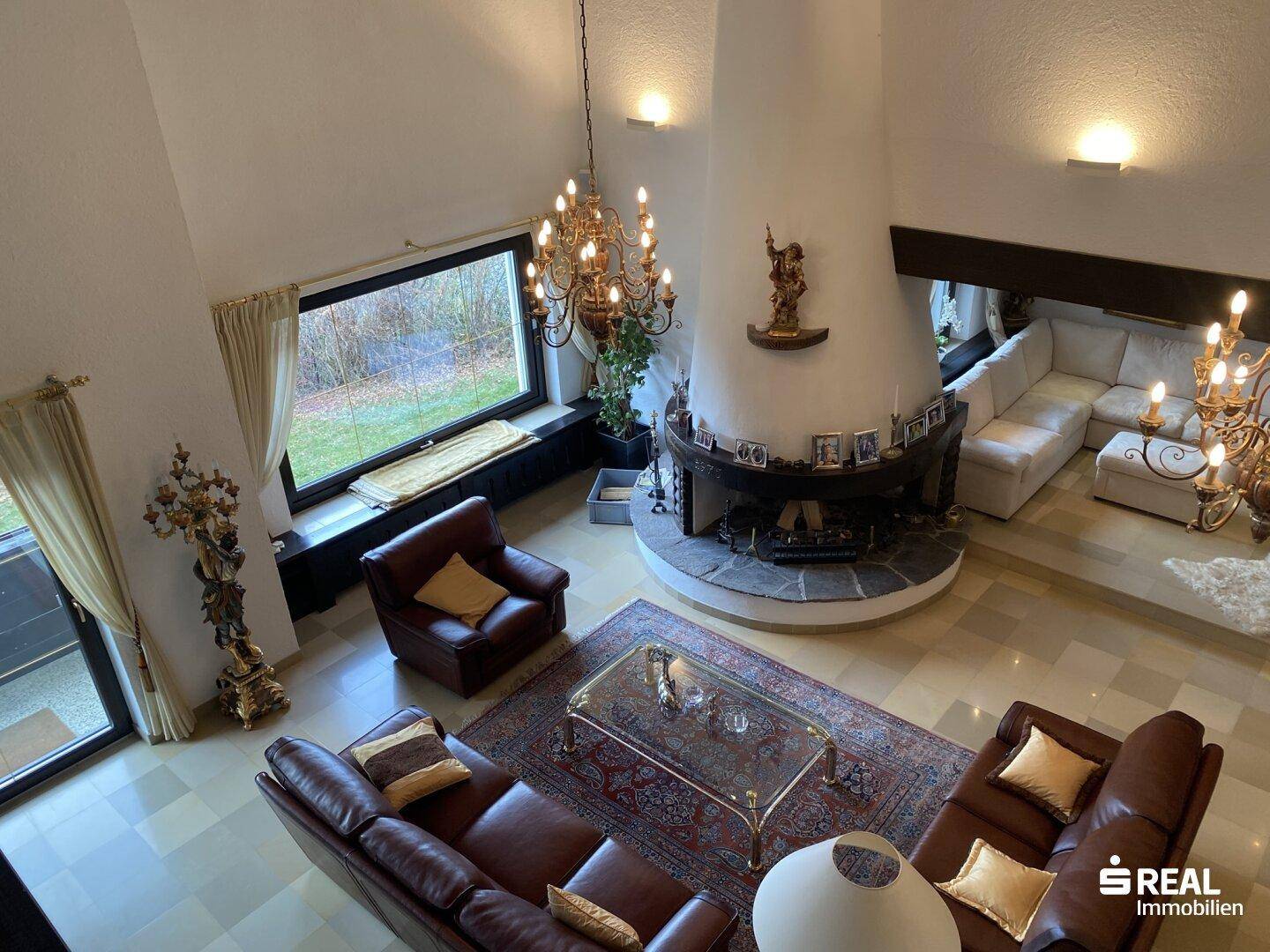 Beeindruckender Wohnbereich mit hoher Decke, großem Kamin und bequemen Ledersofas.