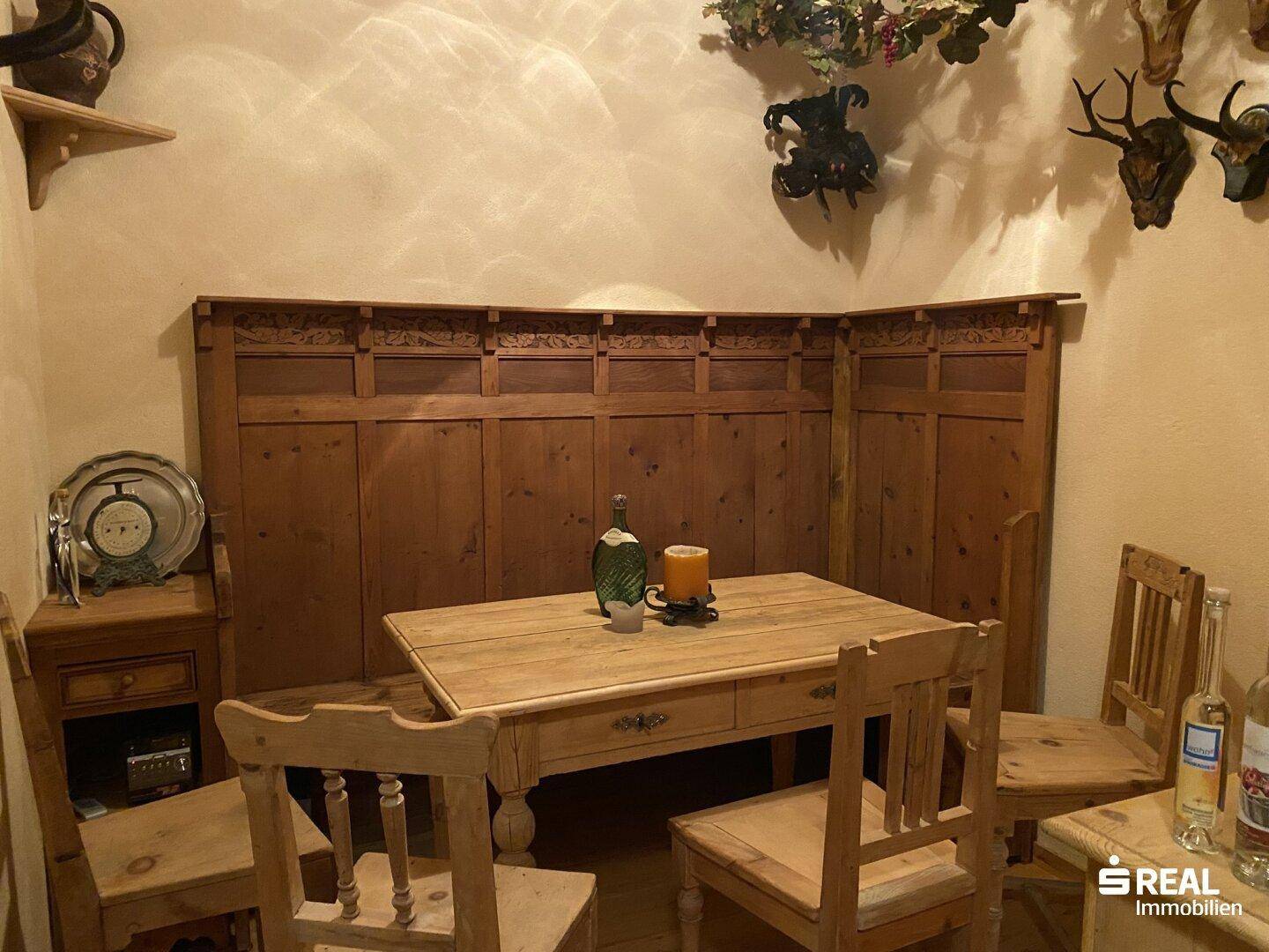 Rustikaler Essbereich mit Holztisch und Bänken, verziert mit traditionellen Jagdtrophäen.