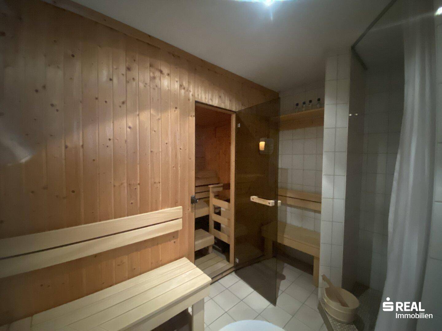 Private Sauna mit Holzbänken und Glaswand, perfekt zur Entspannung und Erholung.