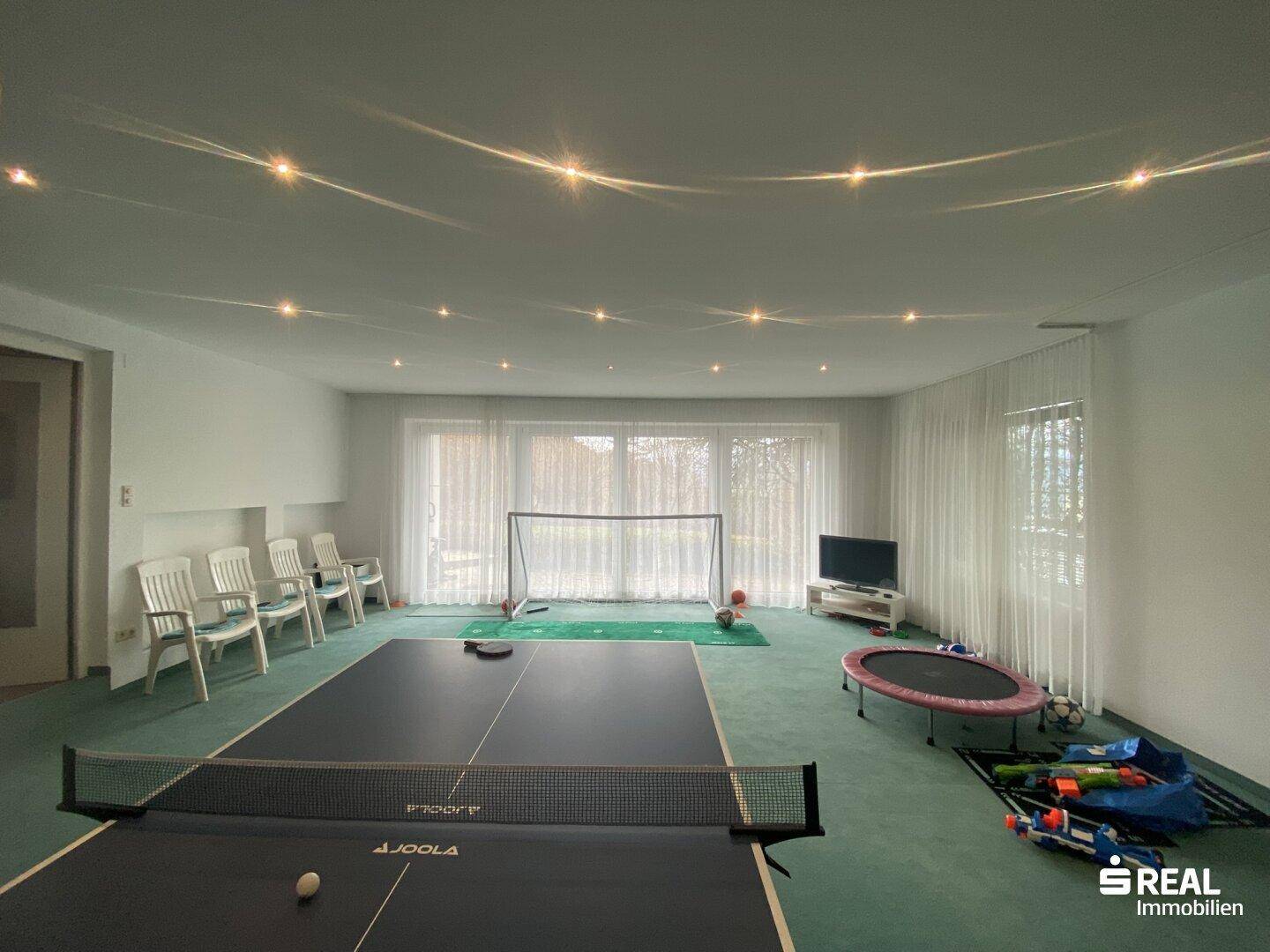 Großer Spielraum mit Tischtennisplatte, Fußballtor und Trampolin, ideal für Freizeitaktivitäten.