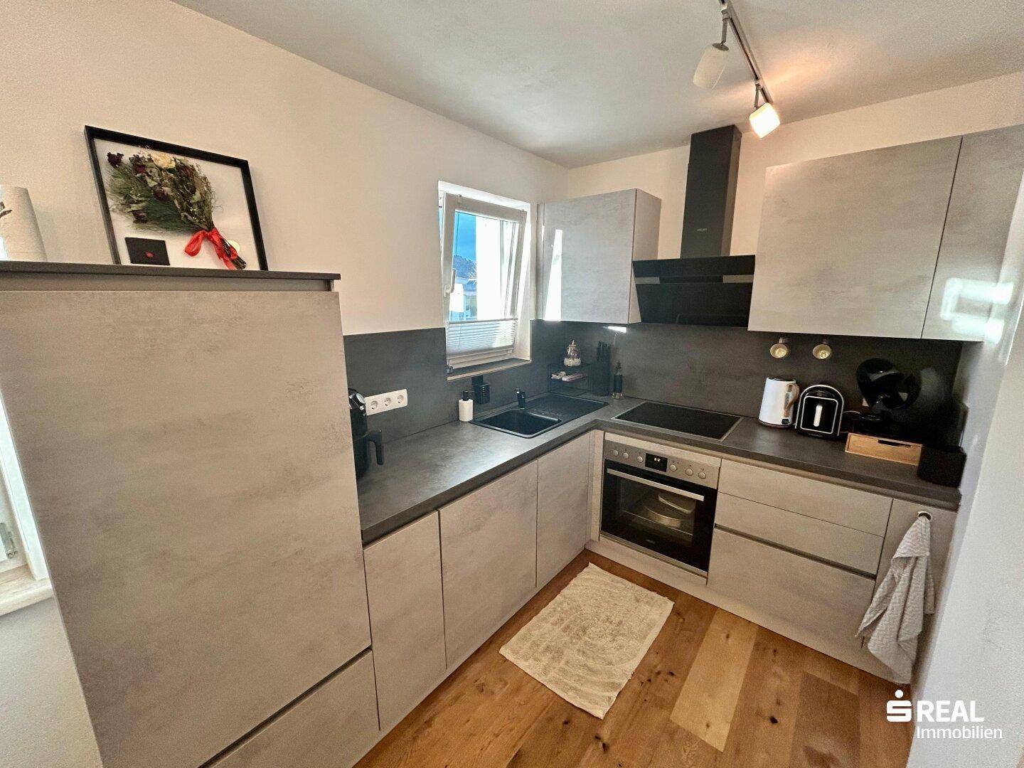 Moderne Einbauküche in Grau mit Holzboden und allen notwendigen Geräten für den täglichen Gebrauch.