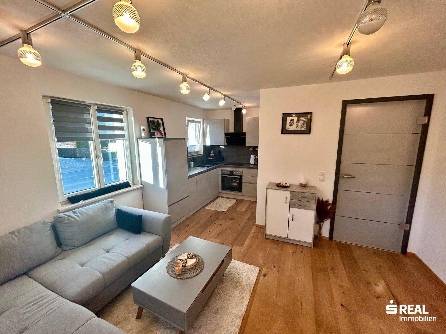 Offener Wohn- und Essbereich mit Holzboden und moderner Küche, perfekt für ein zeitgemäßes Wohngefühl.