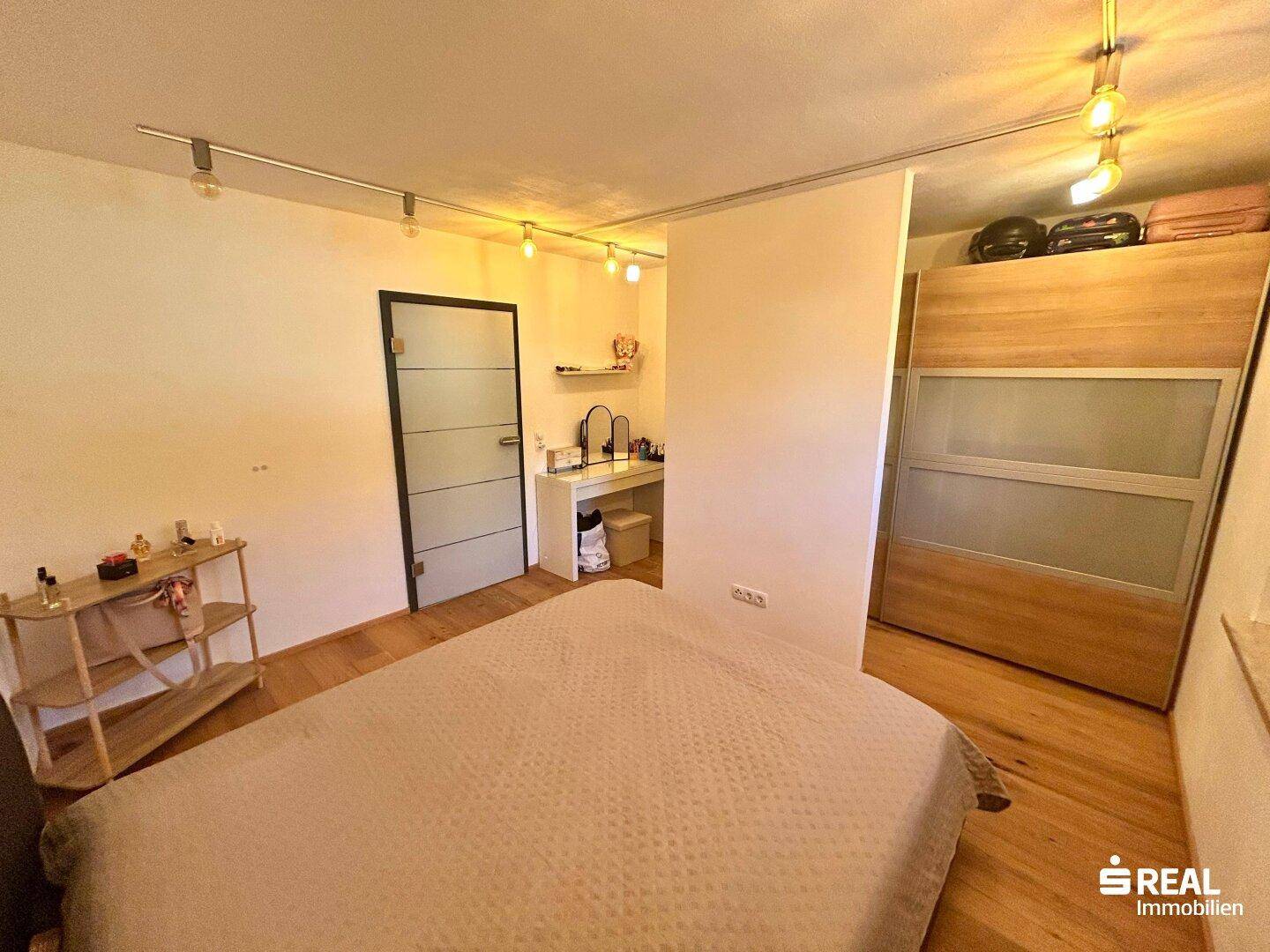 Schlafzimmer mit Holzboden und integriertem Kleiderschrank, bietet praktischen Stauraum.