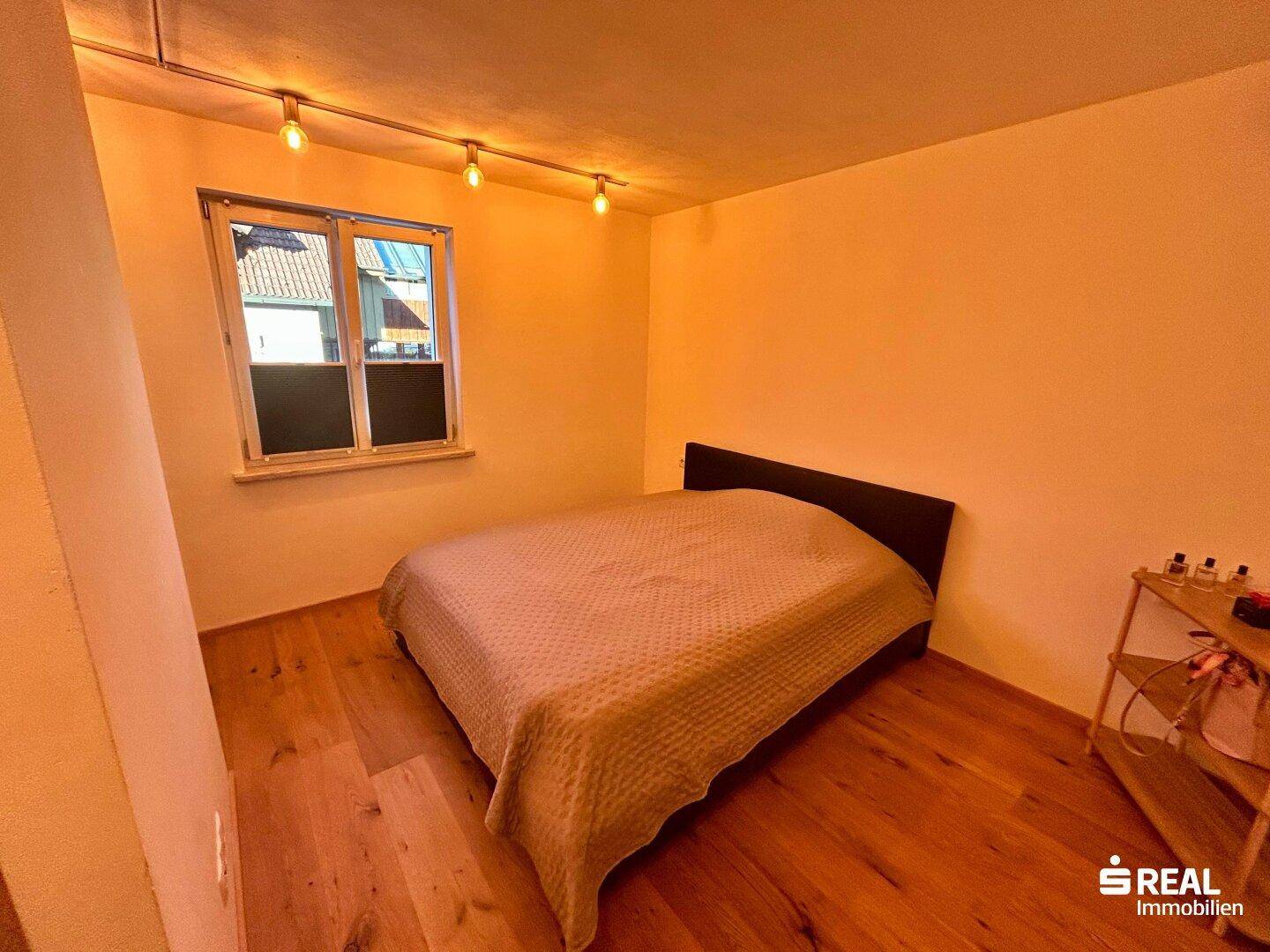 Helles Schlafzimmer mit Holzboden und Fenster, sorgt für viel Tageslicht und frische Luft.