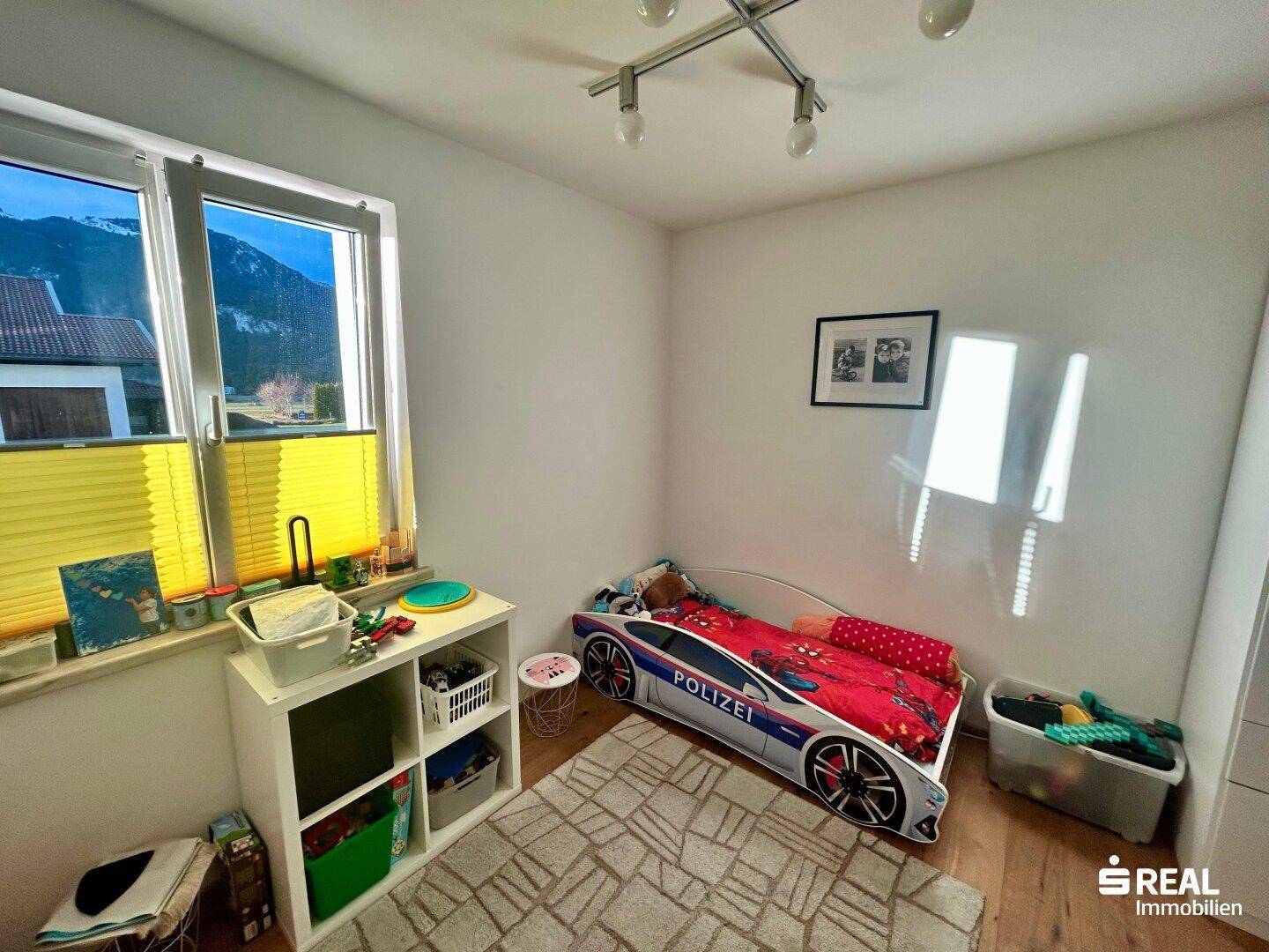 Kinderzimmer mit Holzboden und Blick auf die Berge, bietet eine helle und freundliche Umgebung.