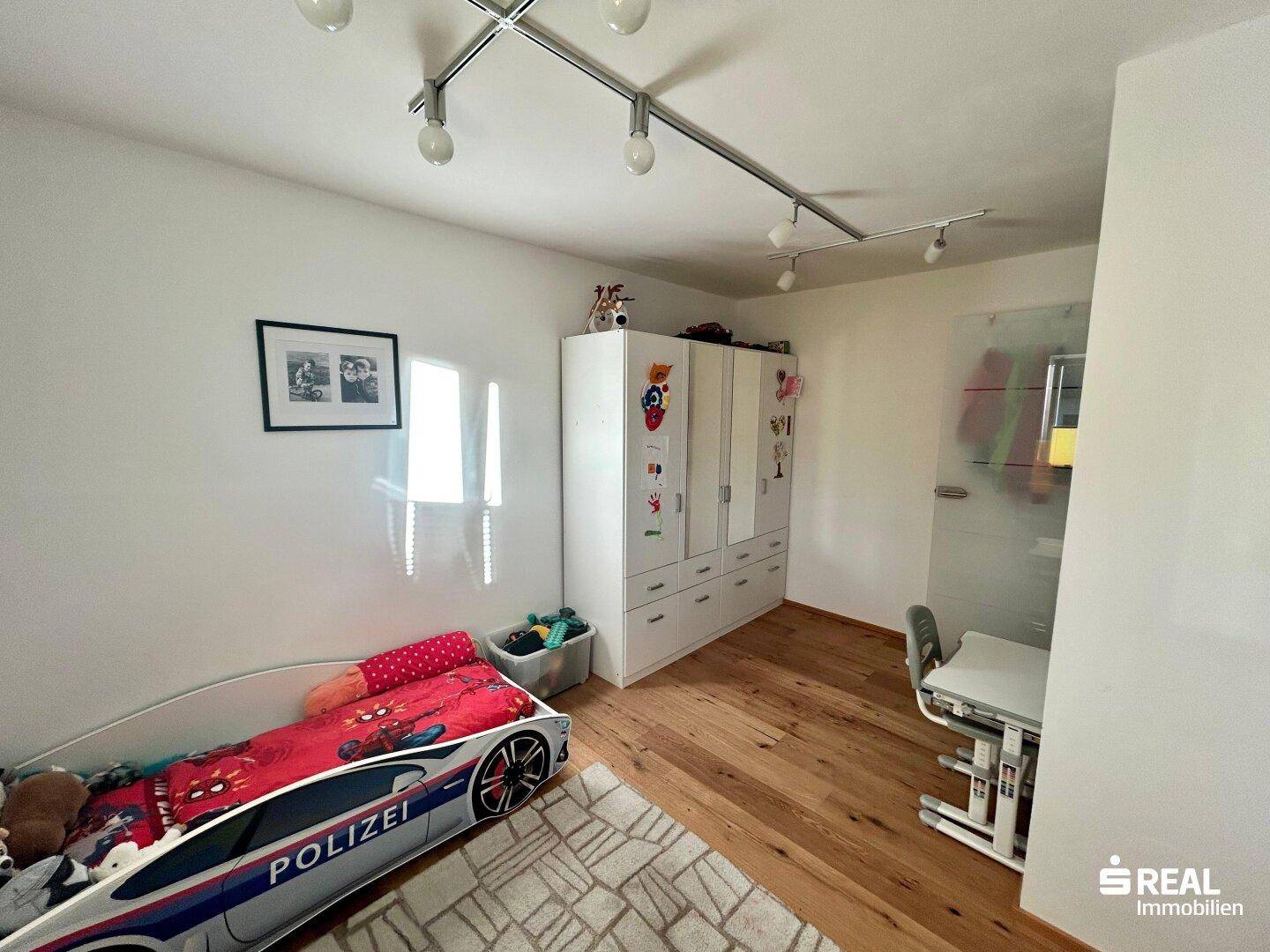 Helles Kinderzimmer mit Holzboden und Schrank, bietet ausreichend Platz zum Spielen und Lernen.