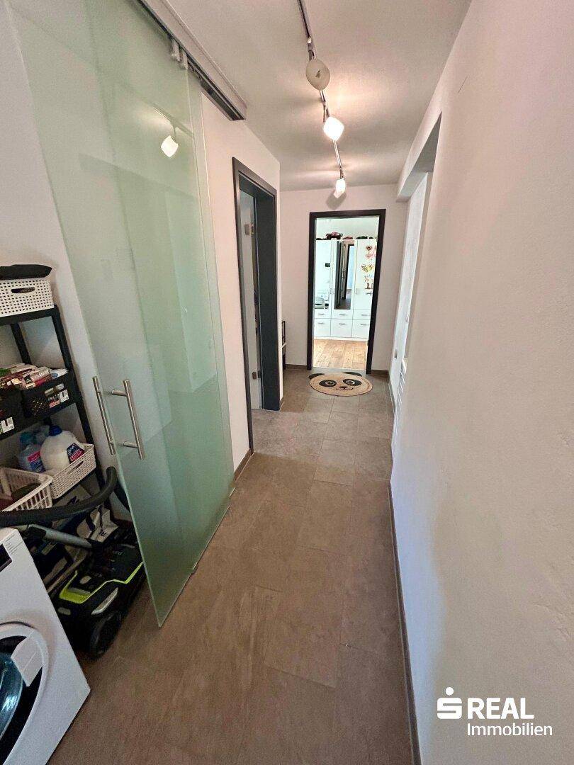 Flur mit Fliesenboden und Schiebetür, bietet Zugang zu verschiedenen Räumen der Wohnung.