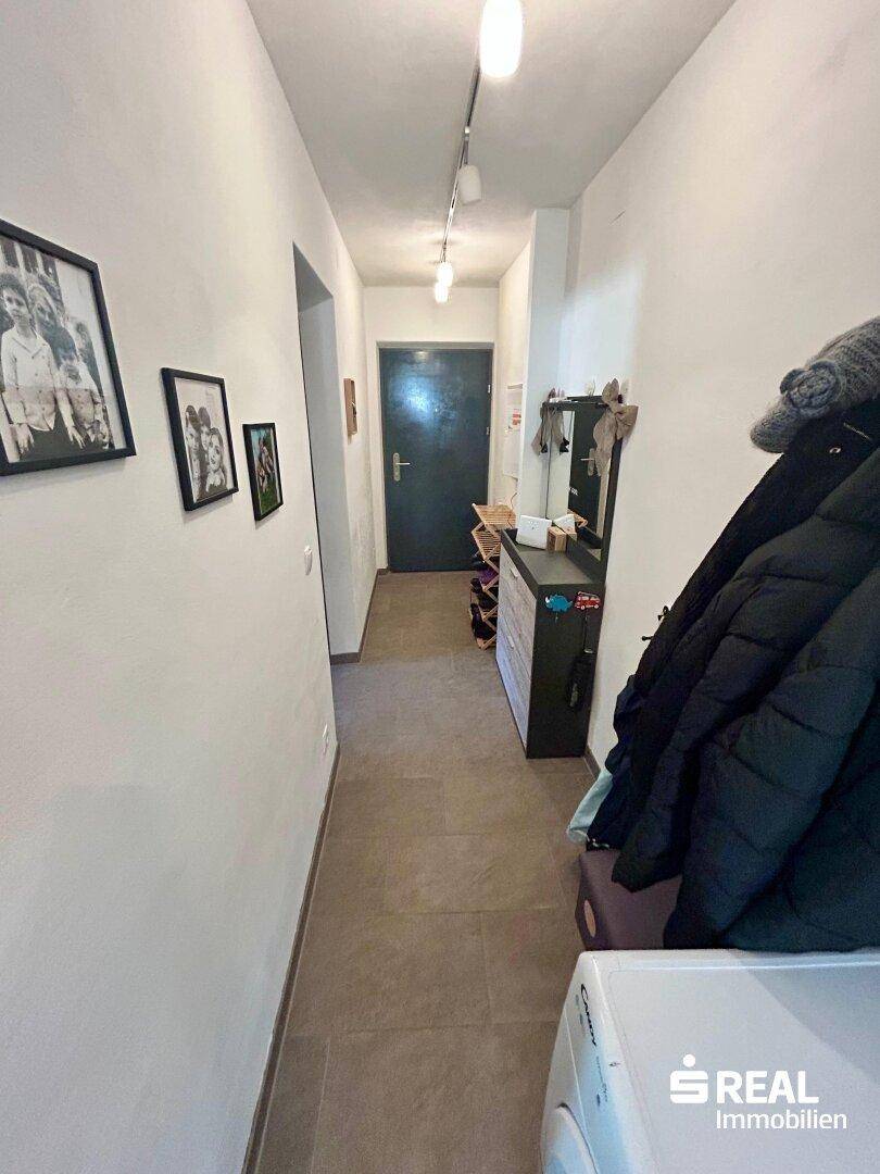 Heller Flur mit Fliesenboden und Garderobe, führt zu den verschiedenen Bereichen der Wohnung.