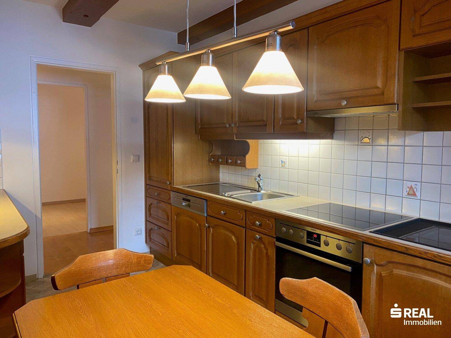 Traditionelle Holzküche mit Einbaugeräten, Fliesenrückwand und Essbereich.