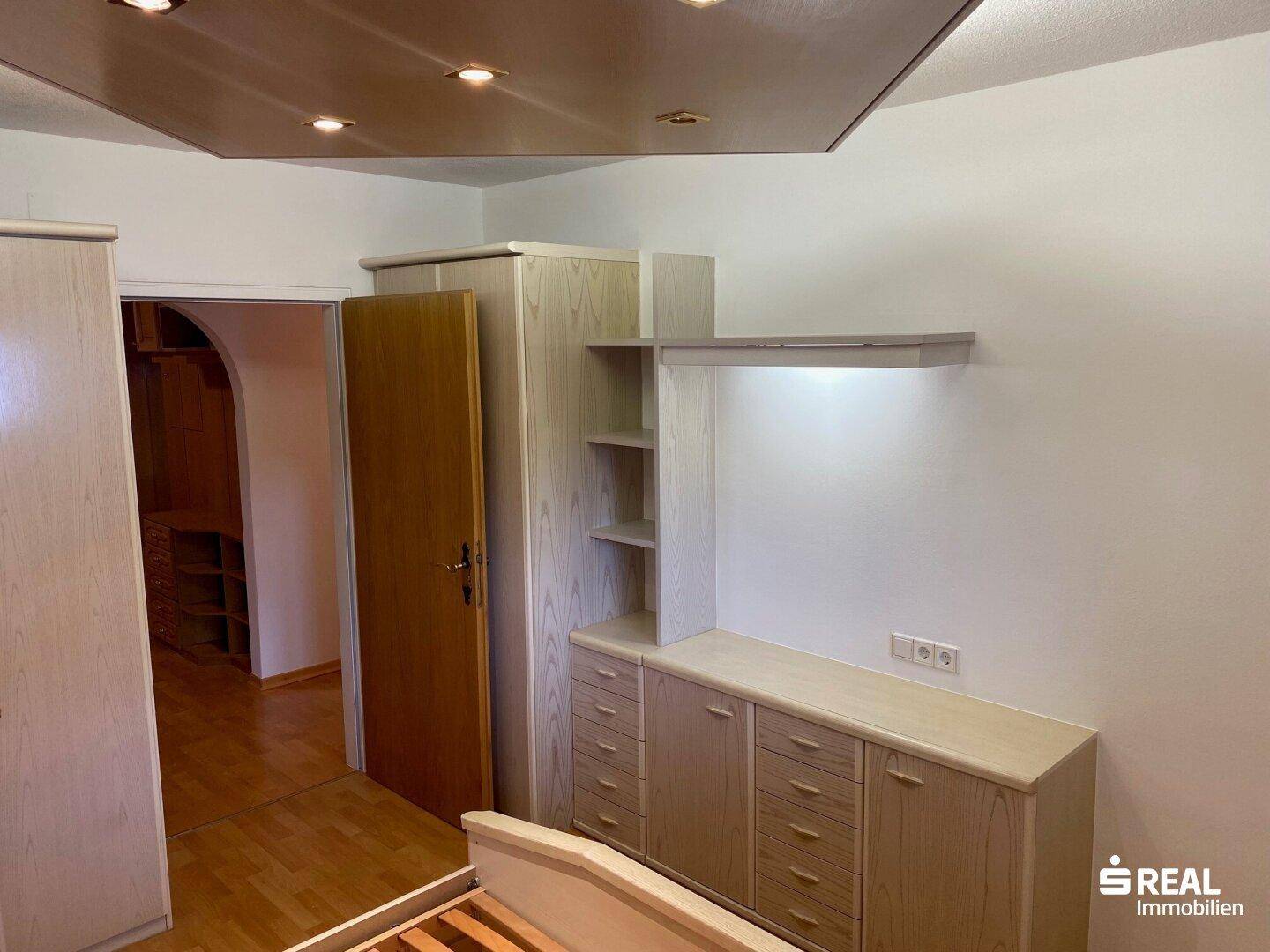 Schlafzimmer mit integrierten Holzschränken und einem Durchgang zu einem weiteren Raum.