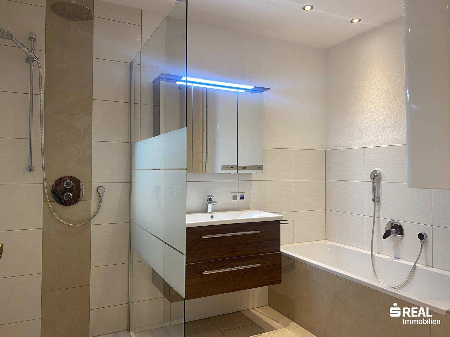 Modernes Badezimmer mit Badewanne, Duschbereich und einem stilvollen Waschtisch mit Unterschrank.