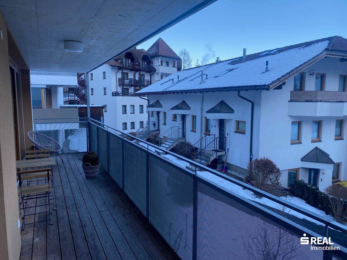 Geräumiger Balkon mit Holzdielen und Panoramablick auf die umliegende Berglandschaft.