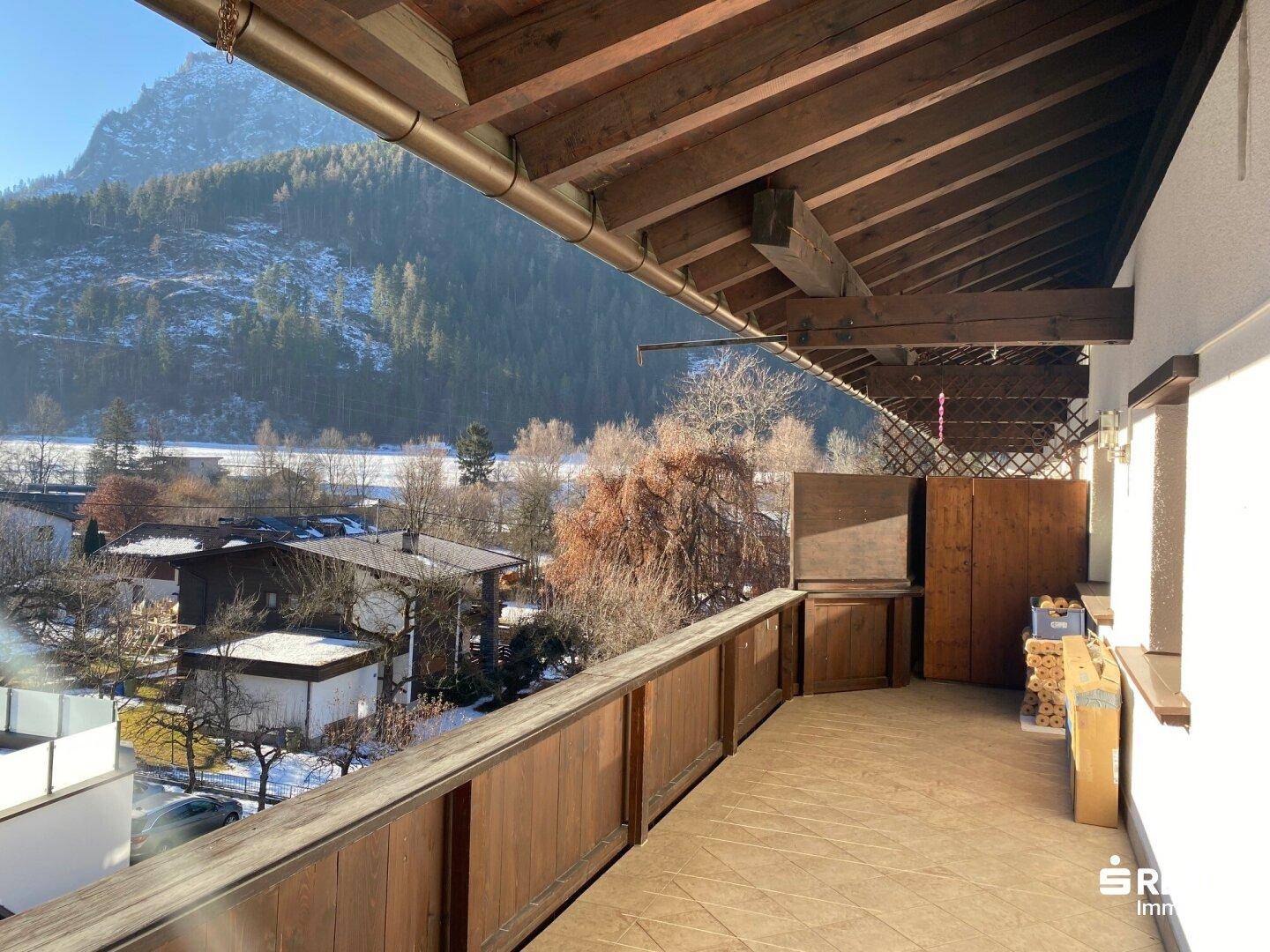 Geräumiger Balkon mit Holzboden und Überdachung, bietet weite Aussicht auf das Tal und die Berge.