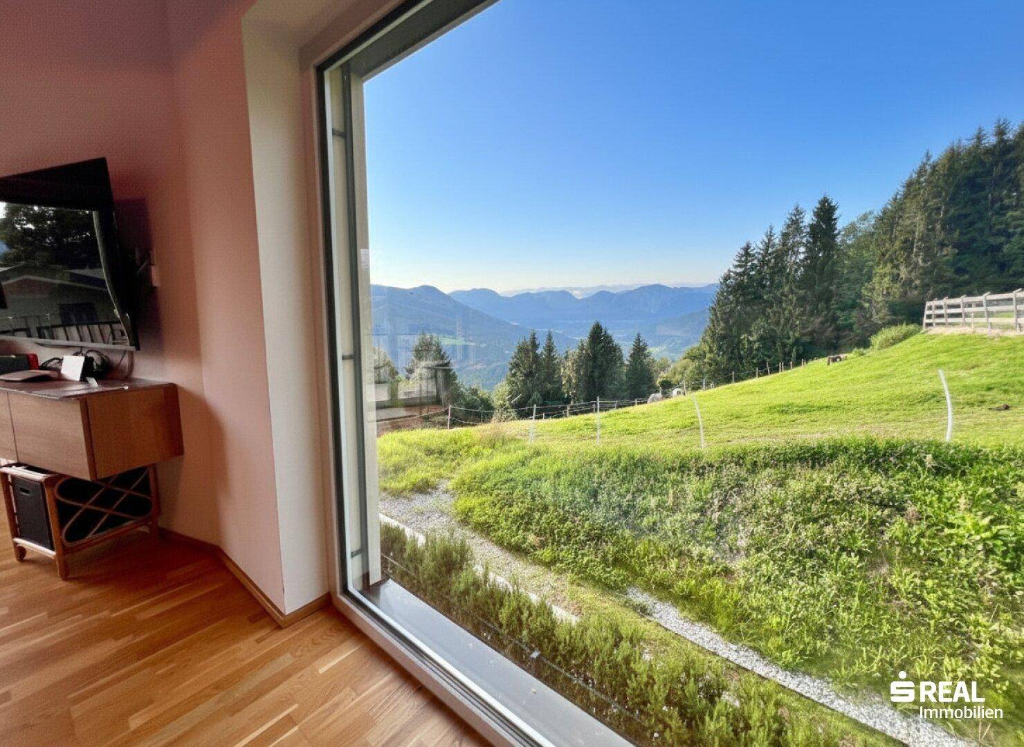 Wohnbereich mit weitem Blick auf die grüne Landschaft und die Berge.