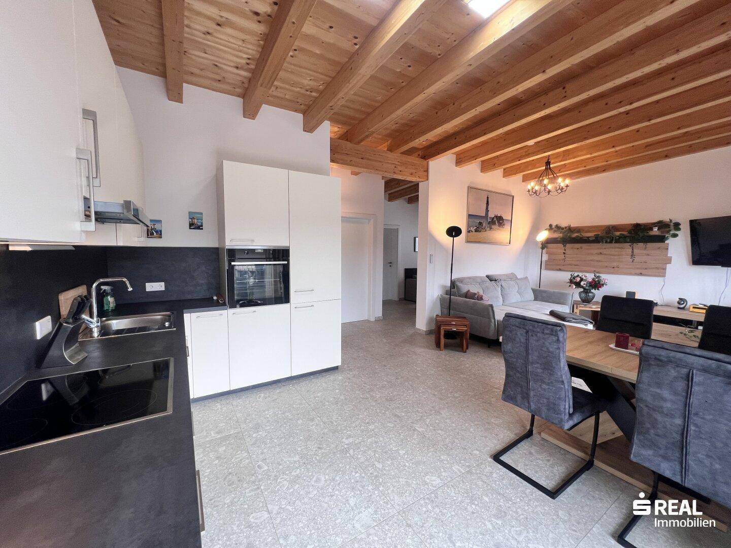 Moderne Einbauküche mit dunkler Arbeitsplatte und Blick in den offenen Wohnbereich.
