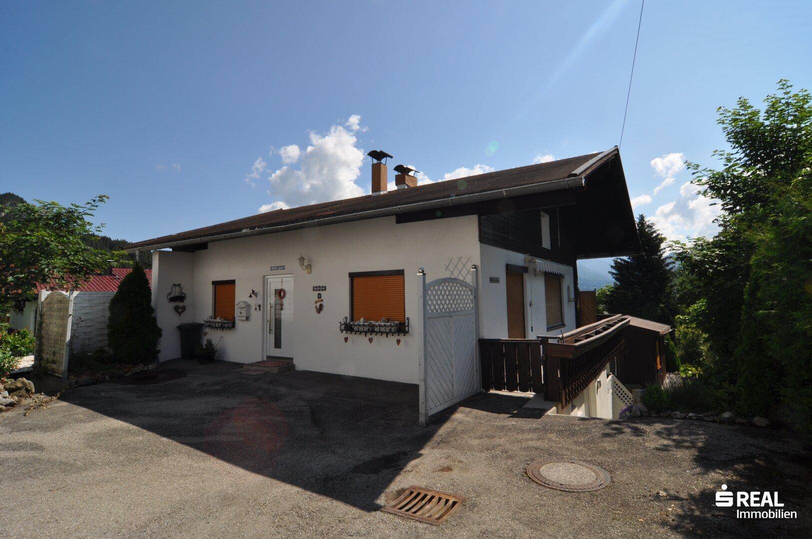 Traditionelles Einfamilienhaus mit Satteldach, Fensterläden und gepflasterter Einfahrt.