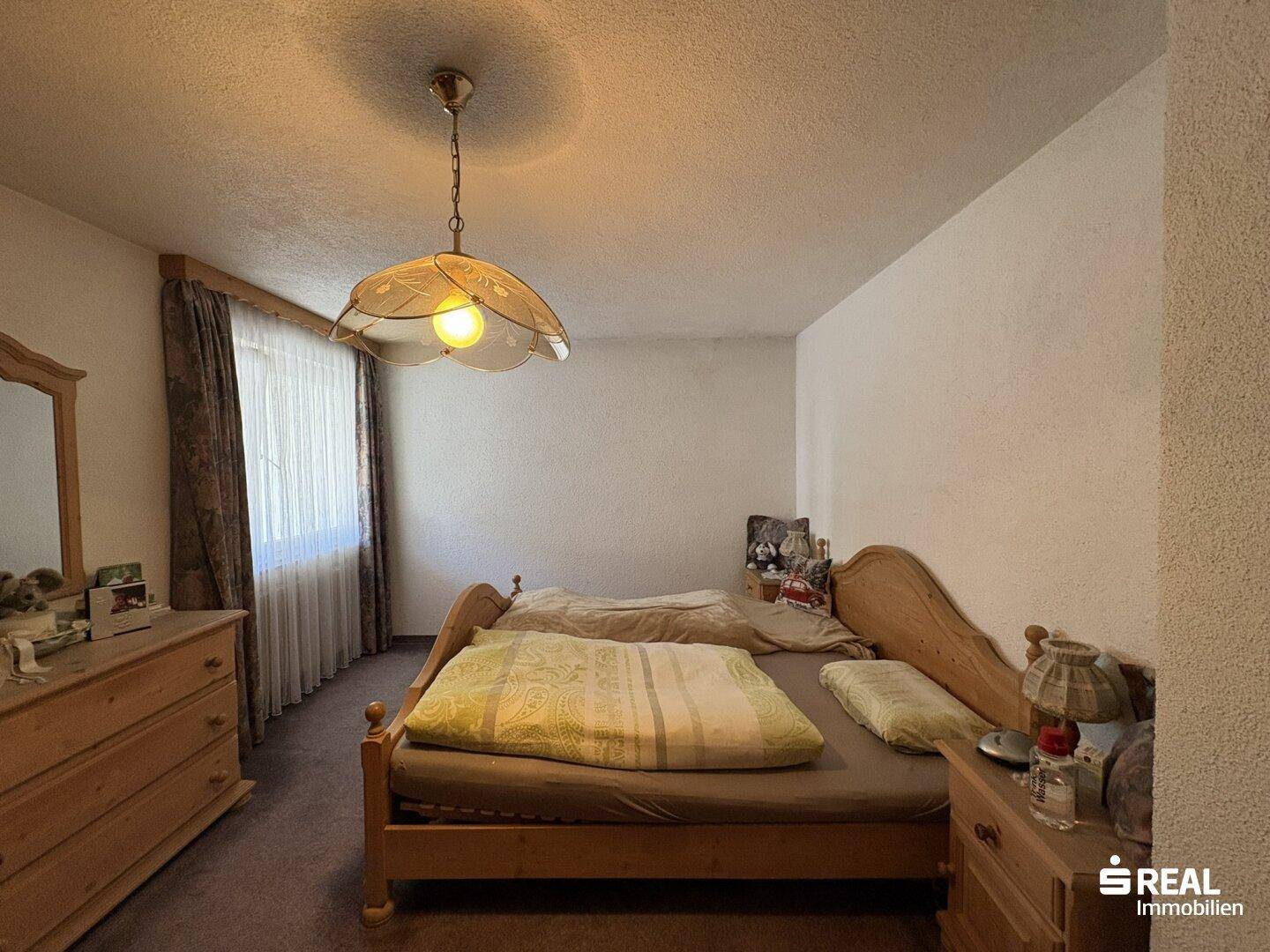 Geräumiges Schlafzimmer mit Doppelbett, Holzmöbeln und einem Fenster für natürliche Beleuchtung.