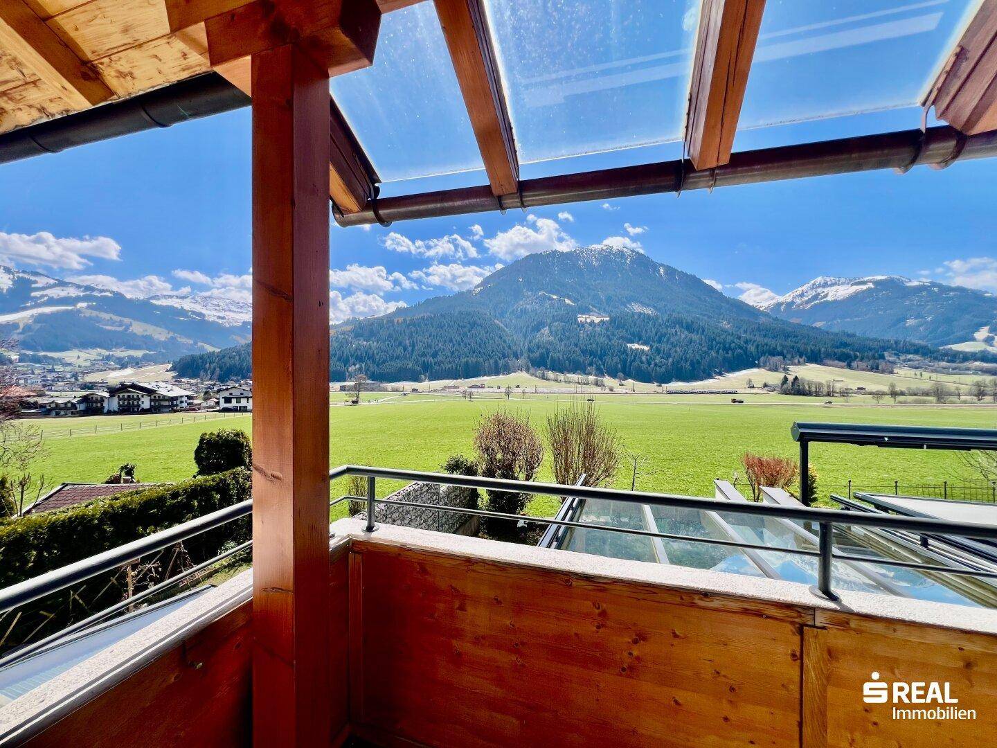 Überdachter Balkon mit Holzkonstruktion und Glasdach, bietet einen weiten Bergblick.