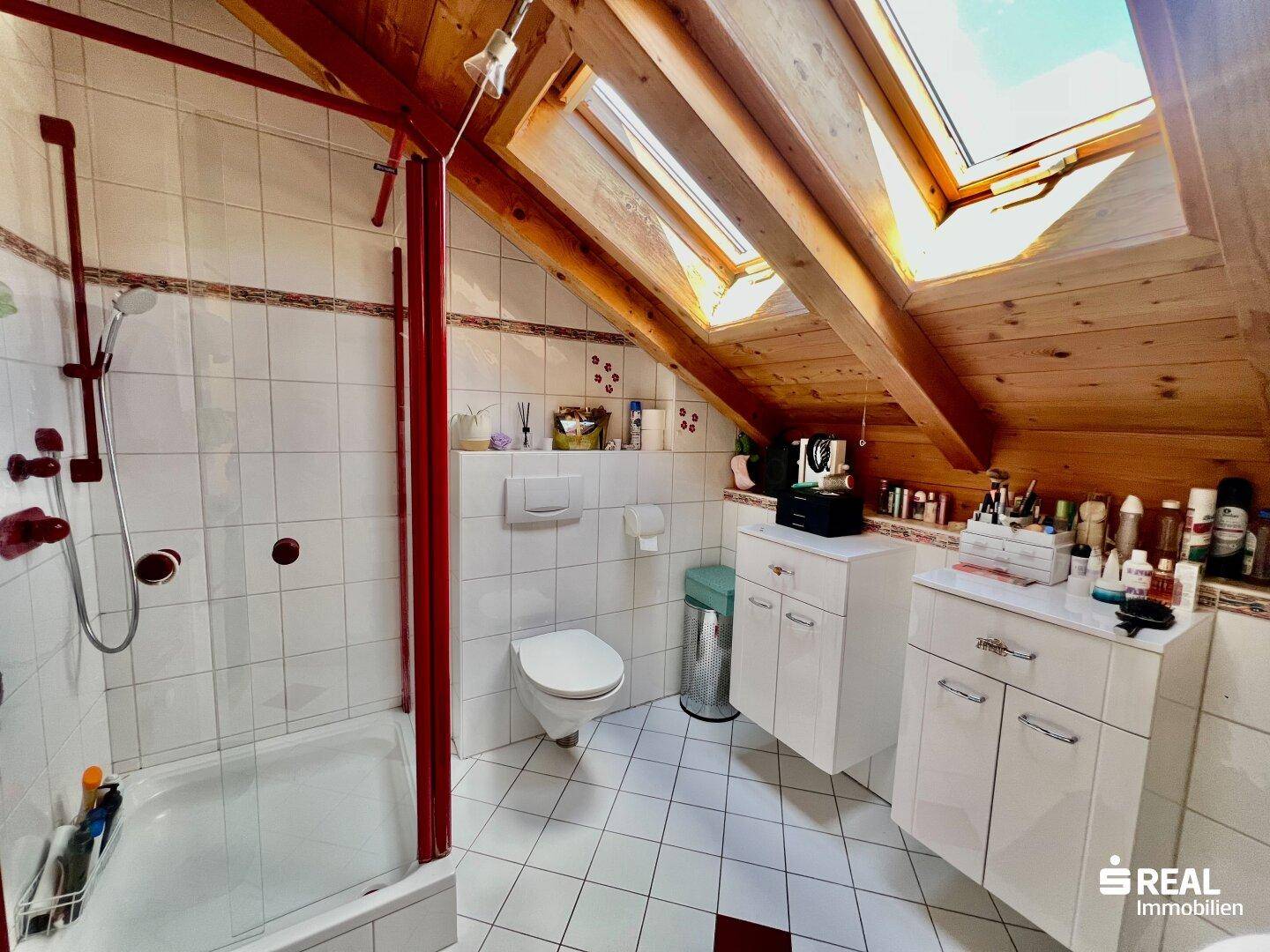 Dachgeschossbad mit Dusche, WC, zwei Waschbecken und Dachfenstern für helle Atmosphäre.