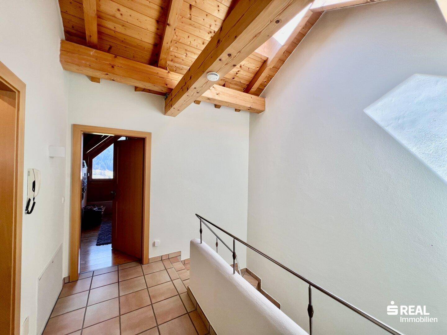Heller Flur mit sichtbaren Holzbalken an der Decke und Fliesenboden im Landhausstil.