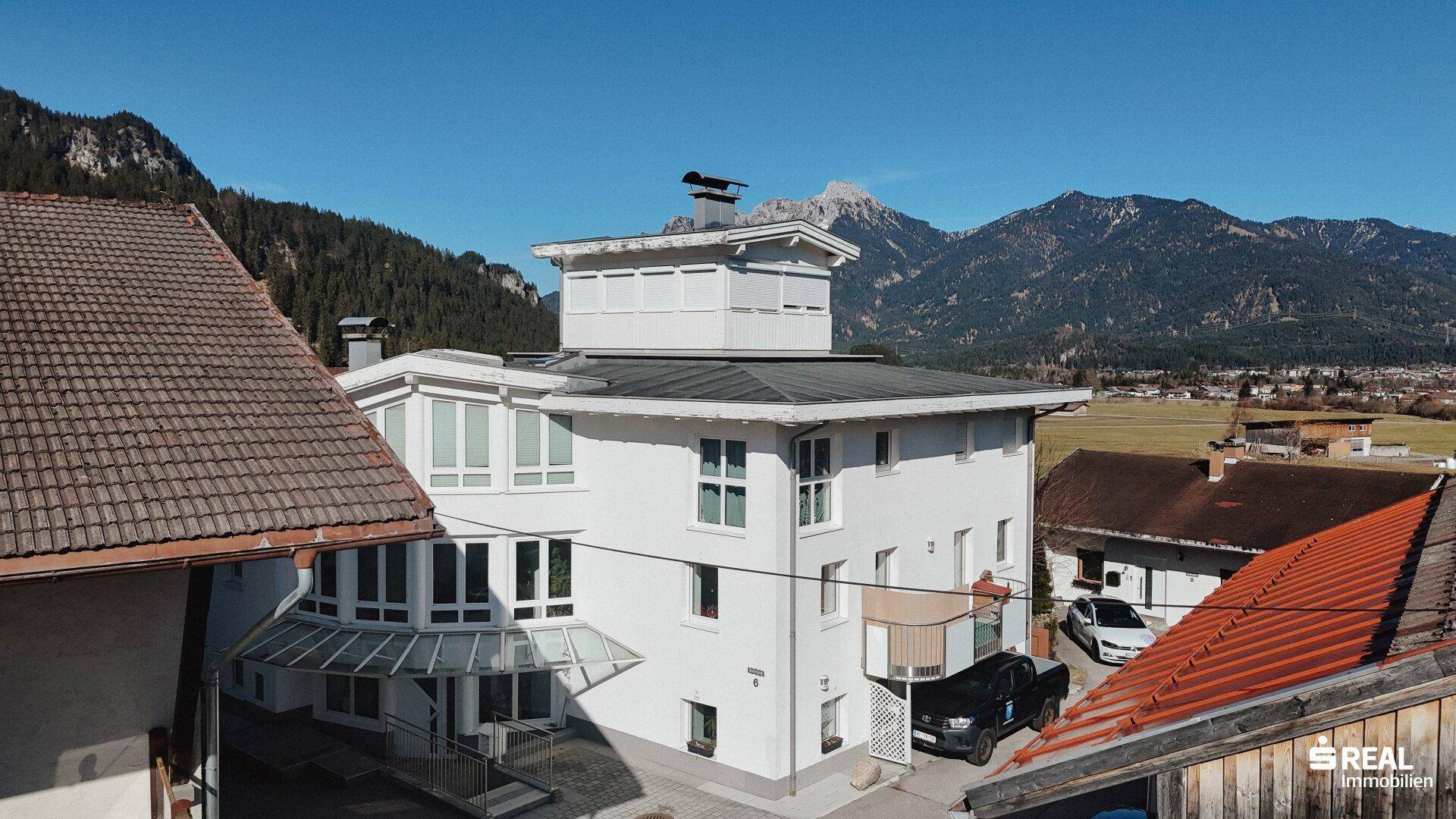 Moderne Architektur eines weißen Gebäudes mit großen Fenstern und Bergblick in sonniger Lage.