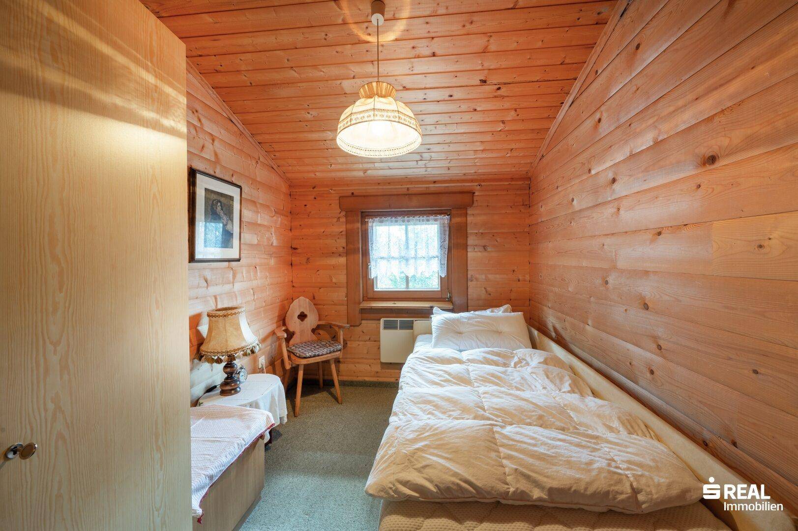 Kleines Schlafzimmer mit Holzvertäfelung, Teppichboden und Einzelbett, ideal als Gästezimmer.